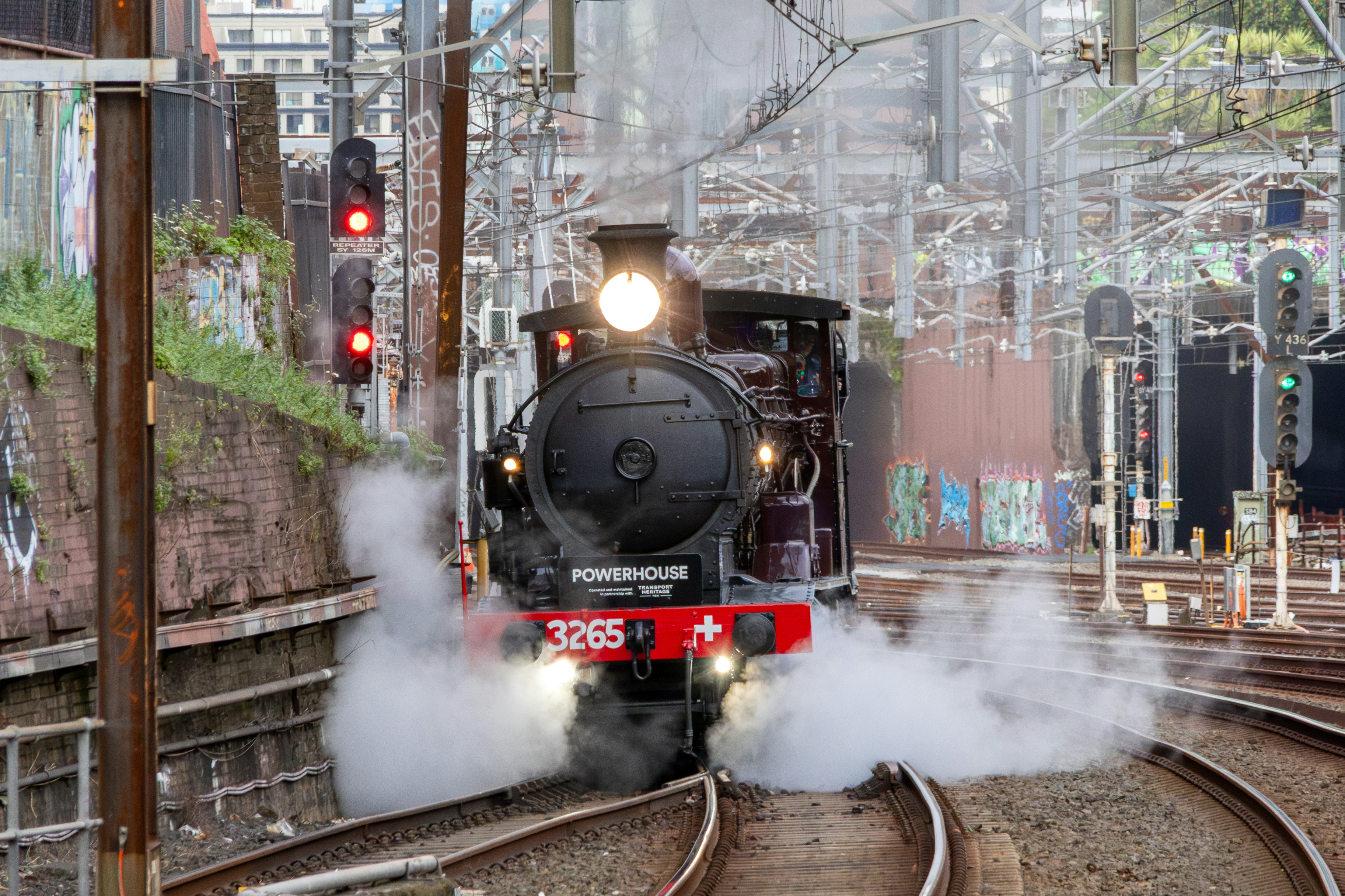 A steam locomotive numbered 3265 moving along railway tracks with billowing white smoke