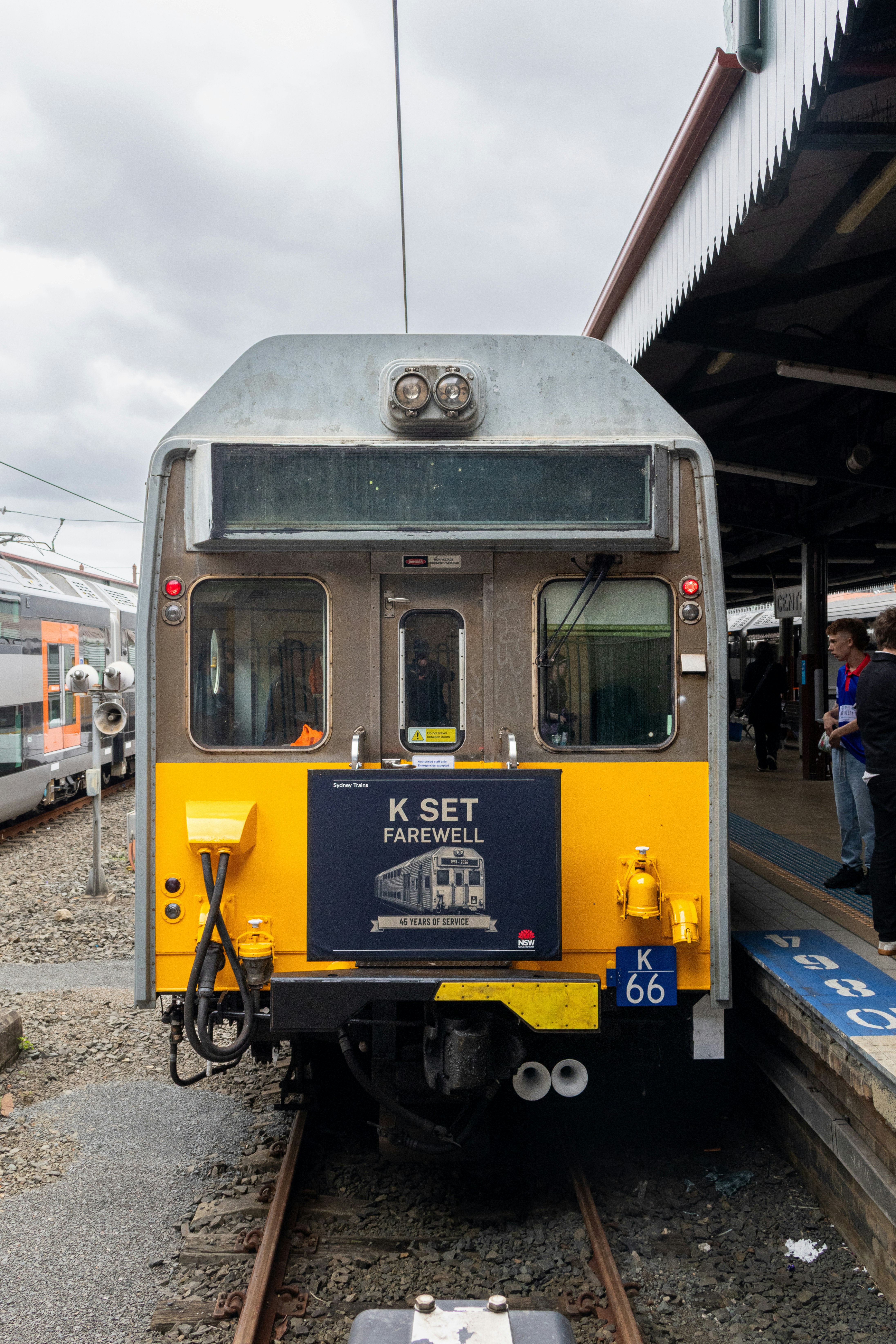A K set train at a station platform with a farewell sign