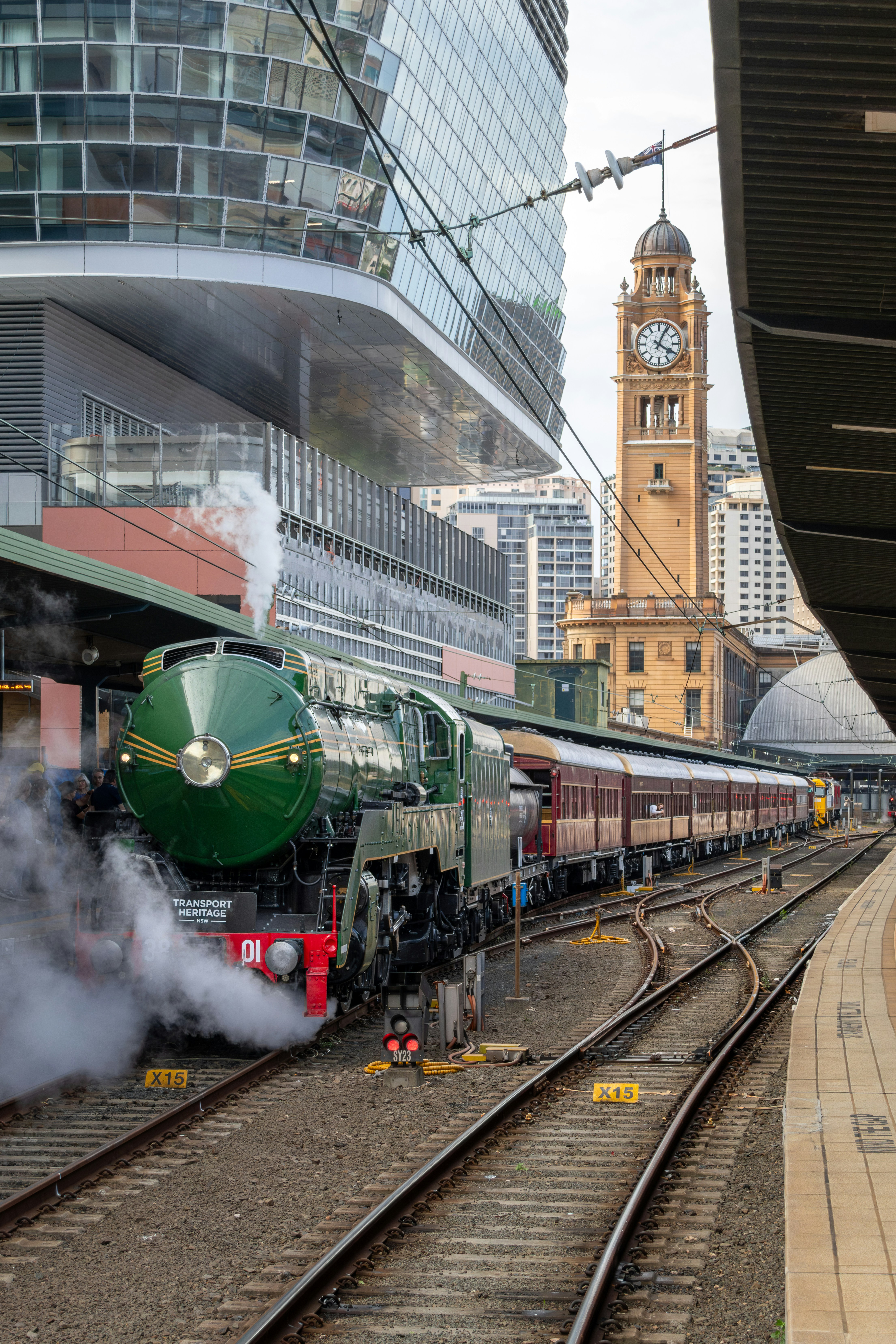 A green steam locomotive at Central Station in Sydney with a clock tower