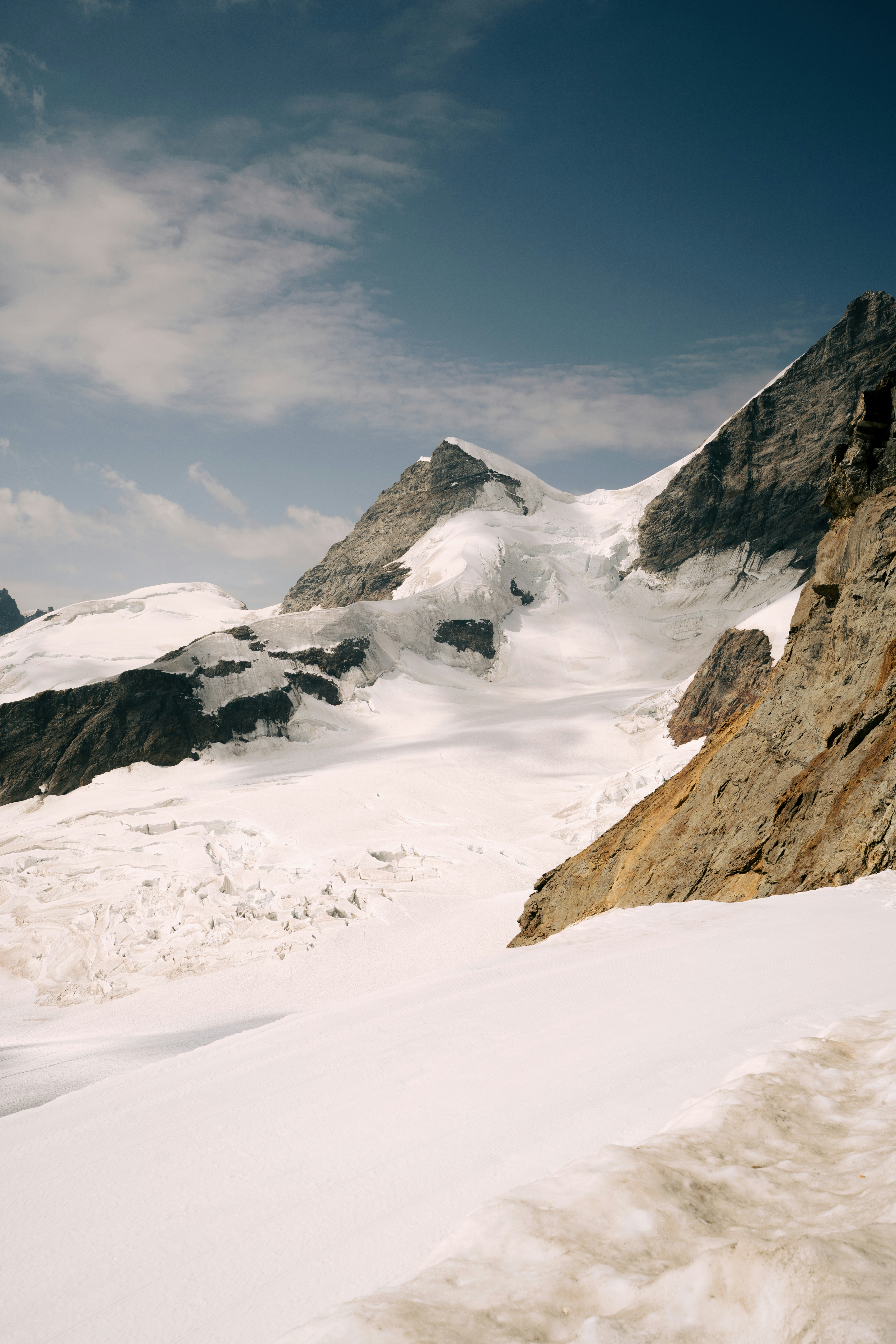 Snowy mountain peaks and a glacier under a blue sky with light clouds