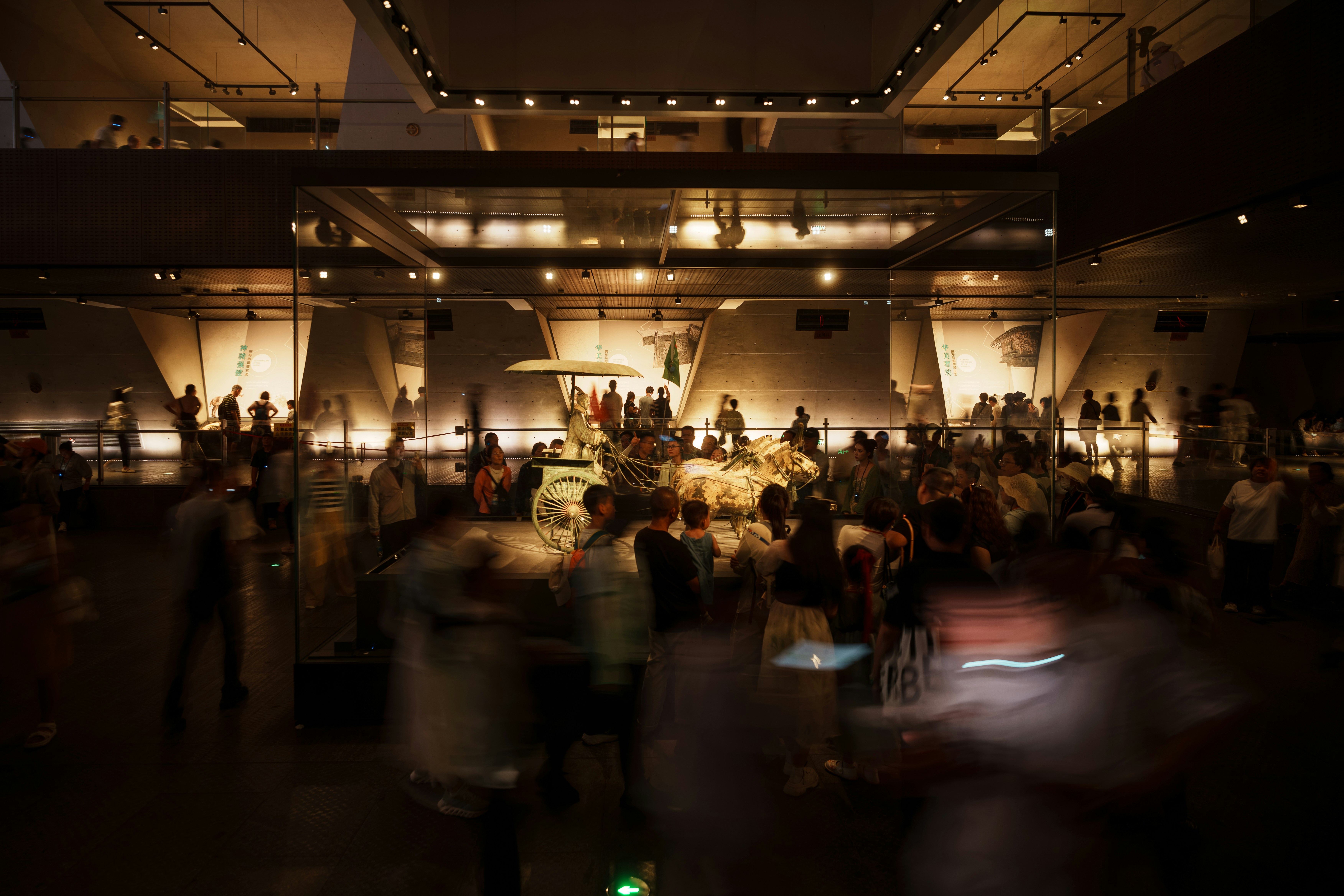 A crowd of people viewing an ancient bronze chariot in a museum gallery