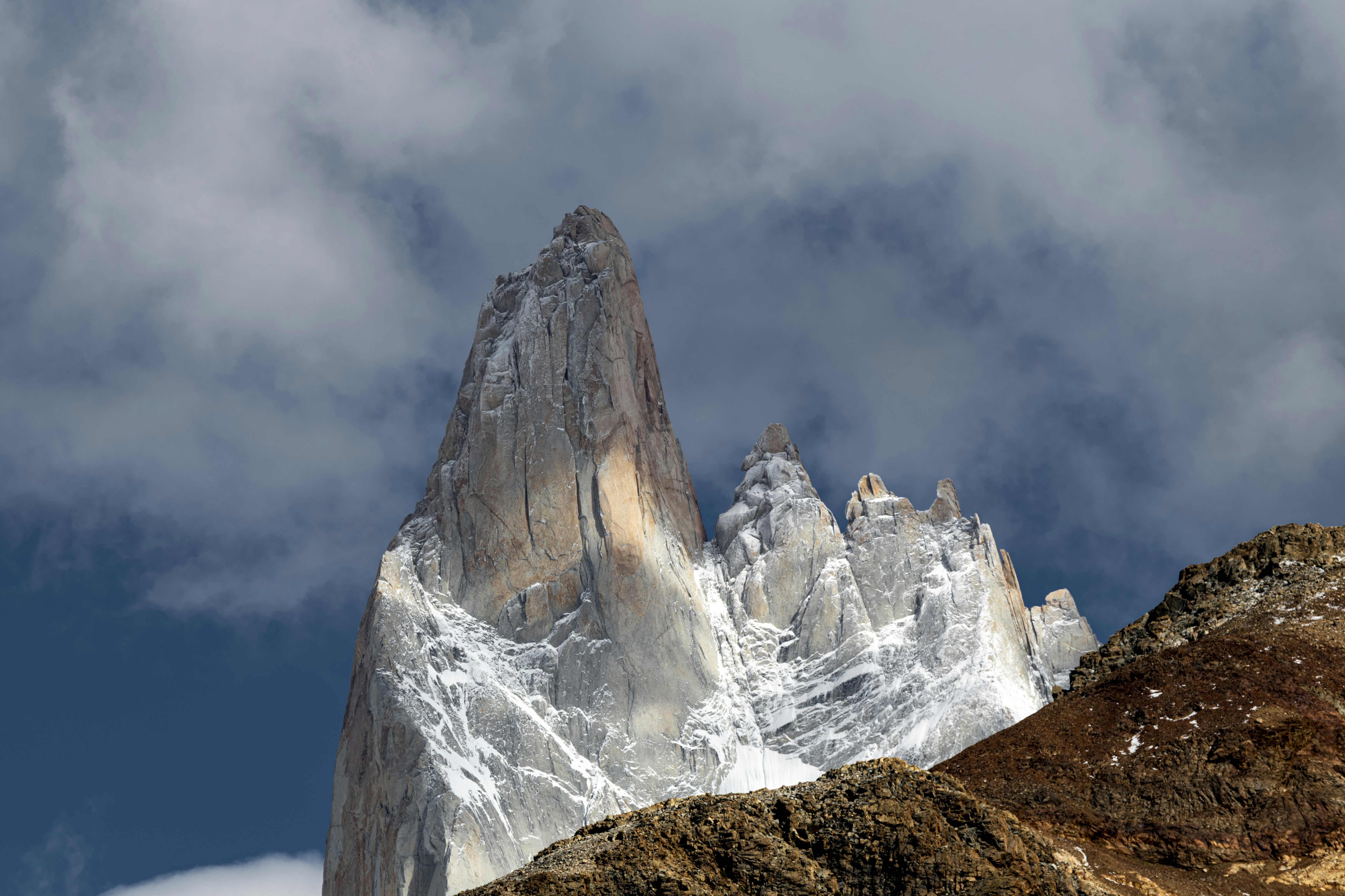 Jagged granite mountain peaks dusted with snow under a cloudy sky