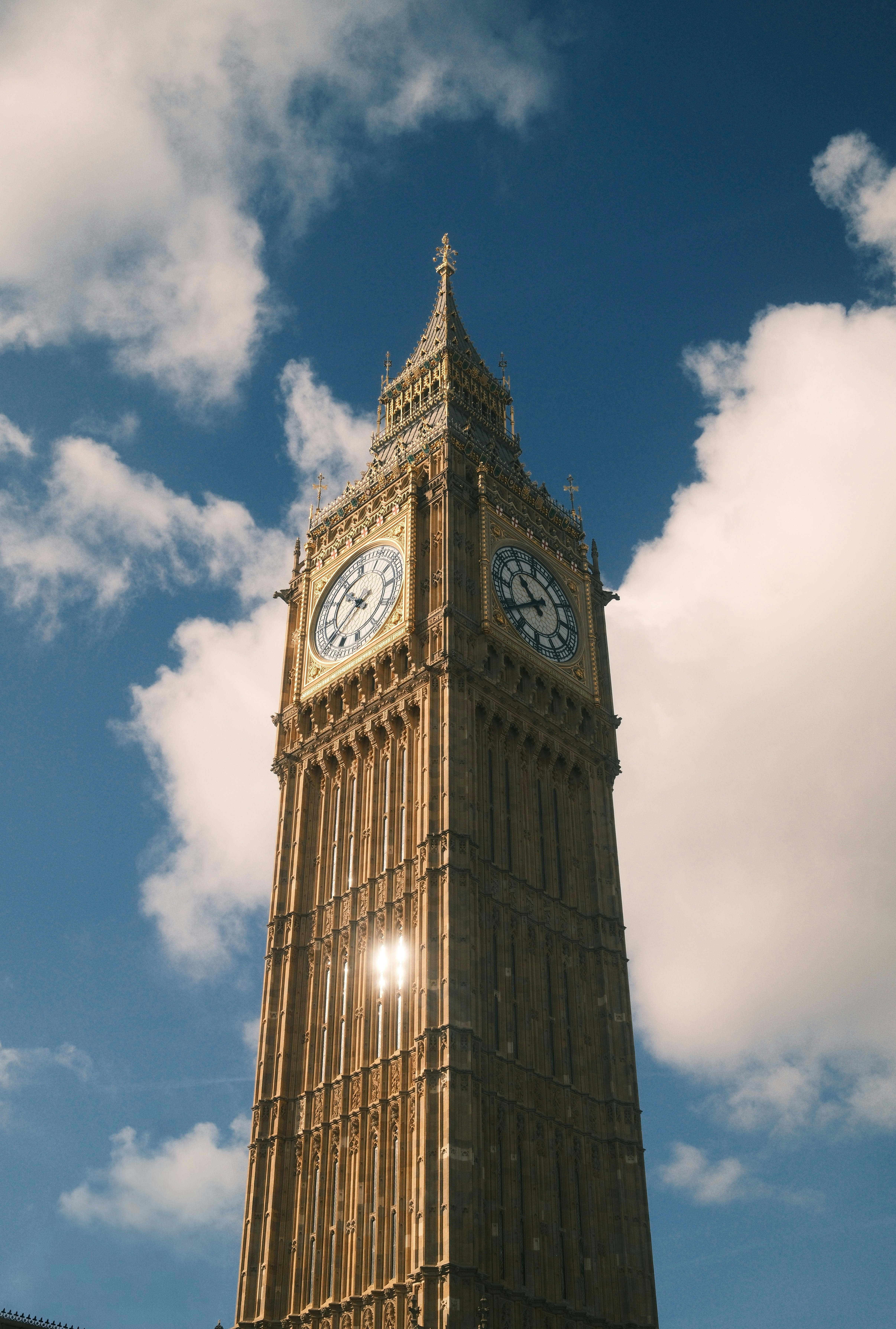 Elizabeth Tower with Big Ben clock faces against a blue sky with clouds