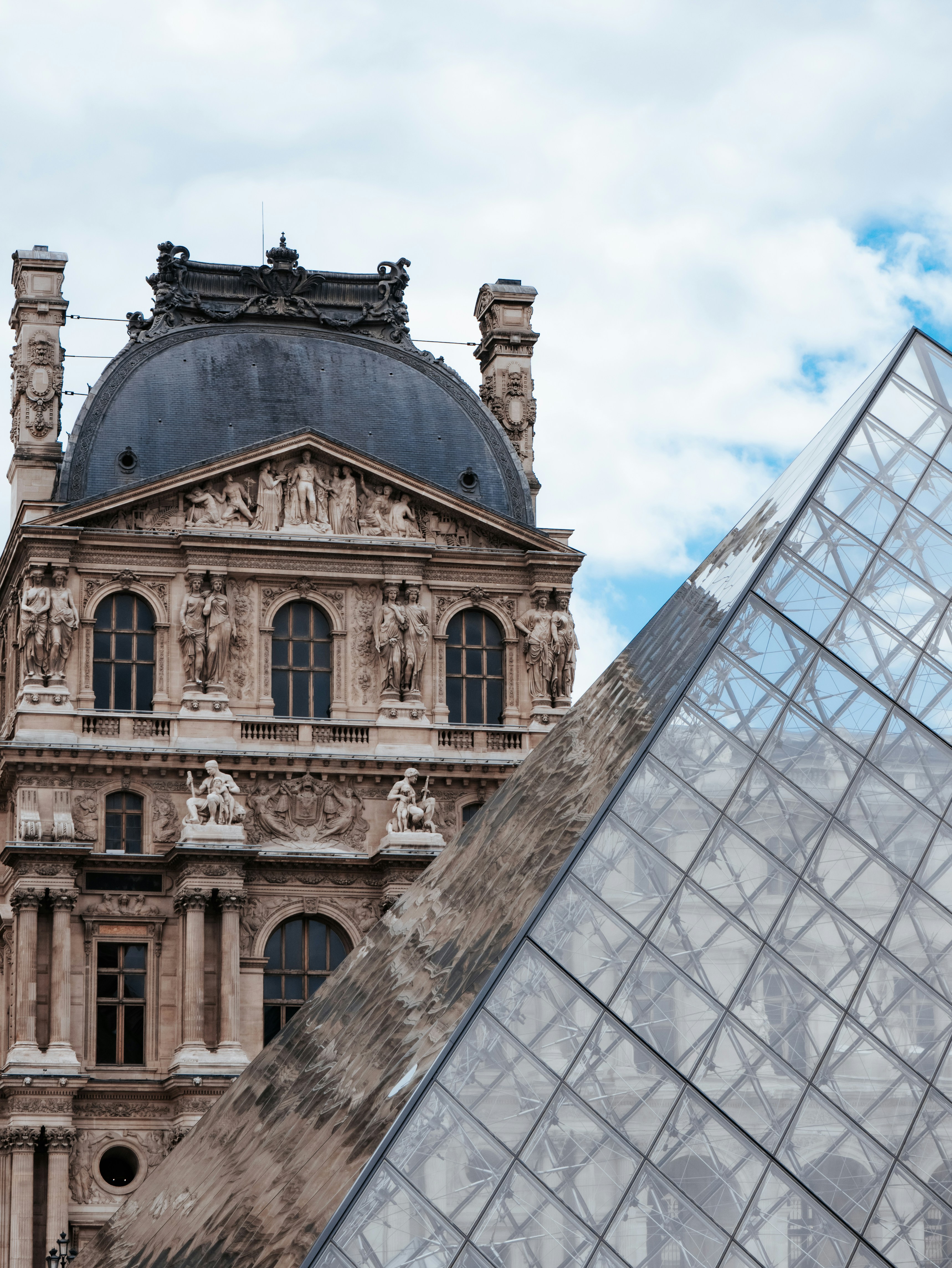 The glass pyramid and ornate stone facade of the Louvre Museum in Paris
