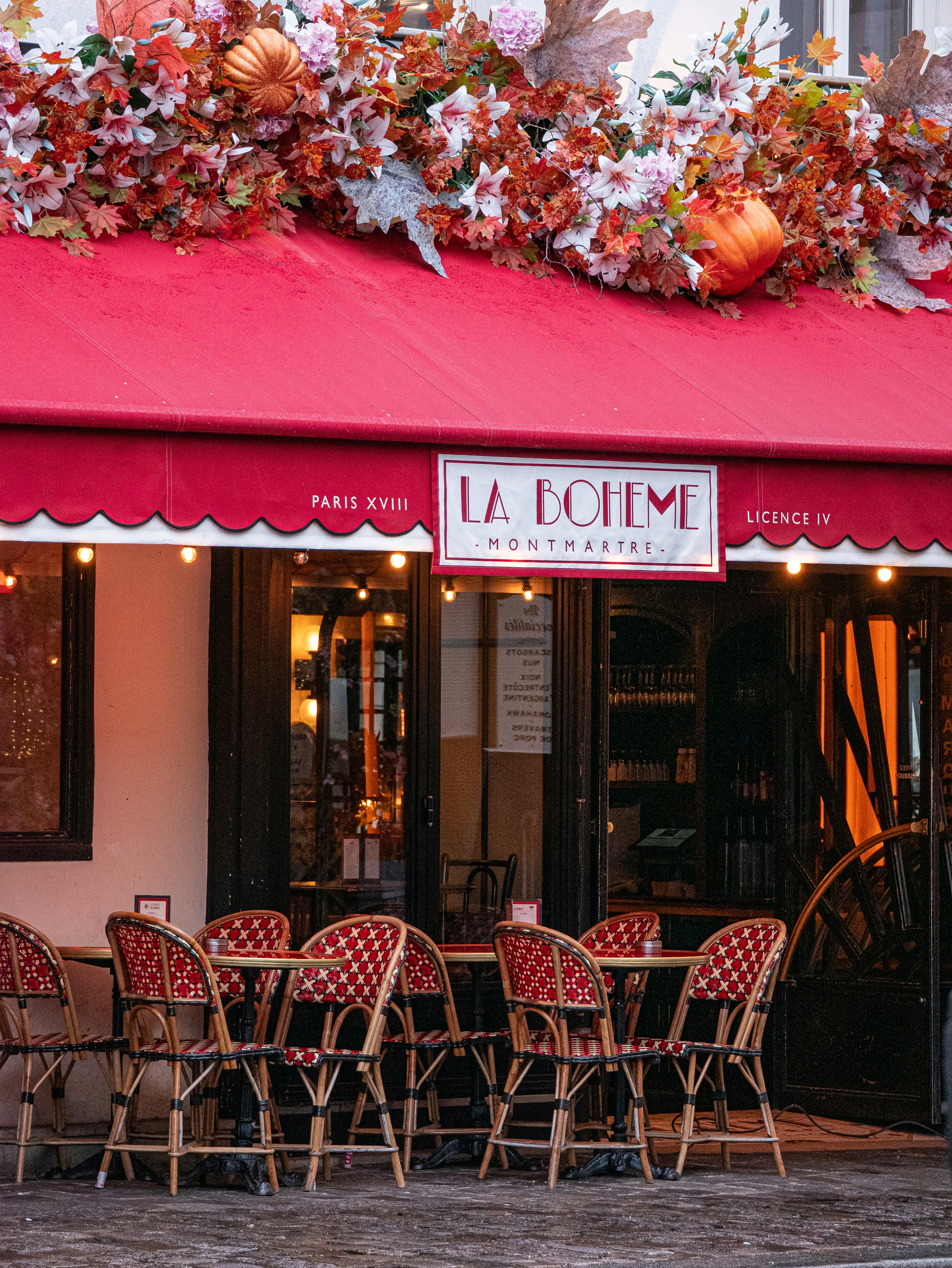 Outdoor cafe seating with red woven chairs under a red awning in Montmartre, Paris