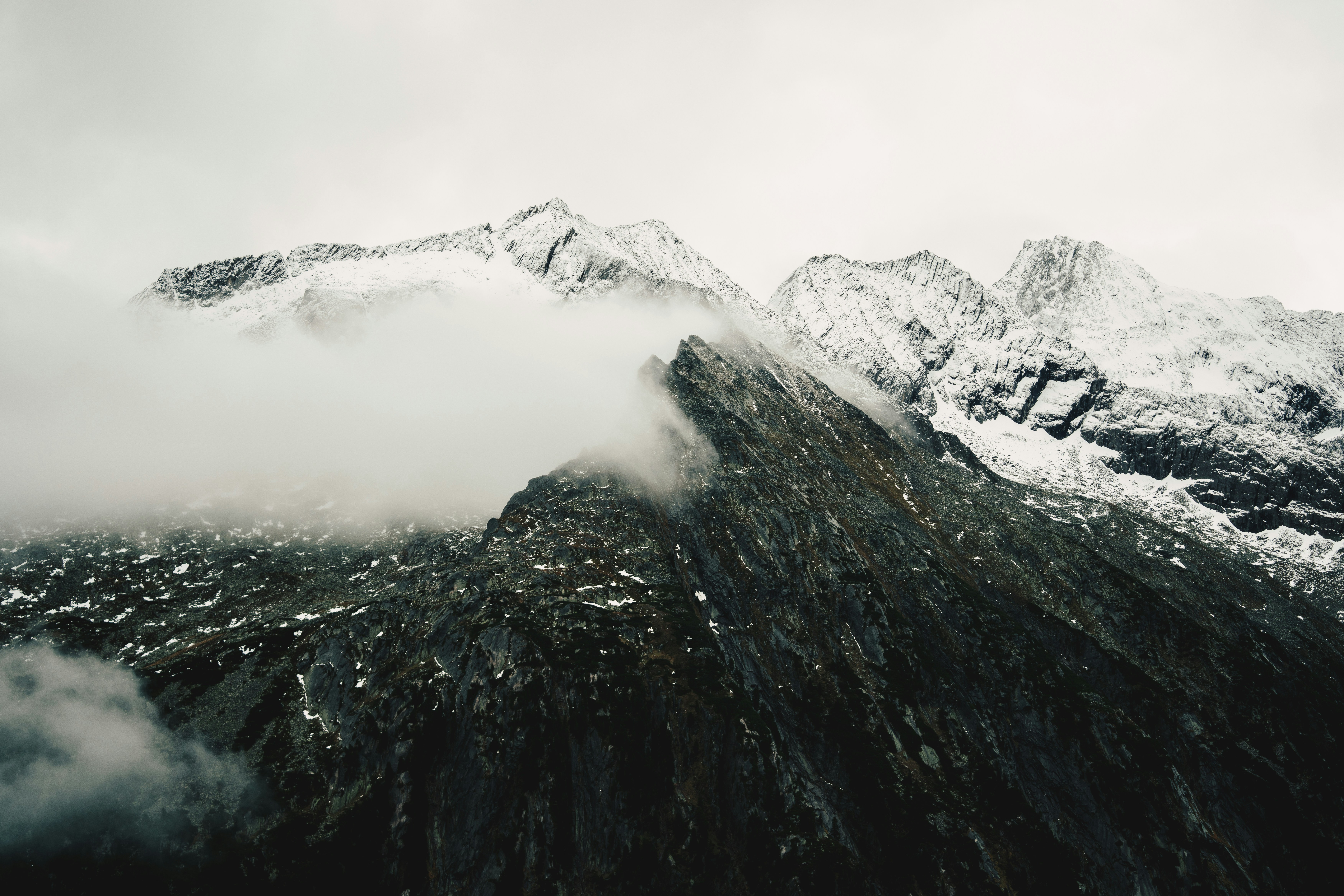 Snow-covered mountain peaks partially obscured by low clouds and mist
