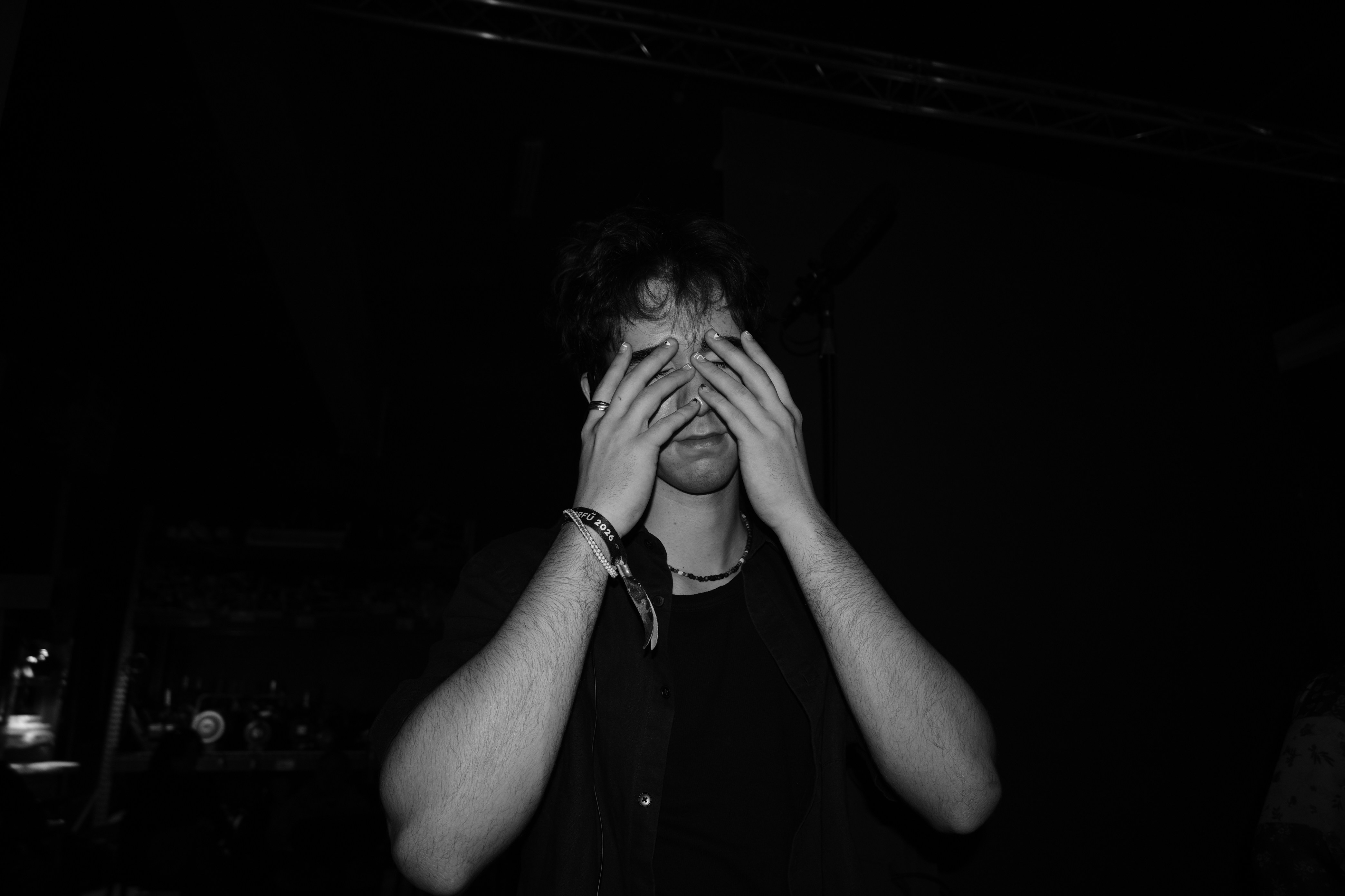 A person in a black shirt covering their face with both hands