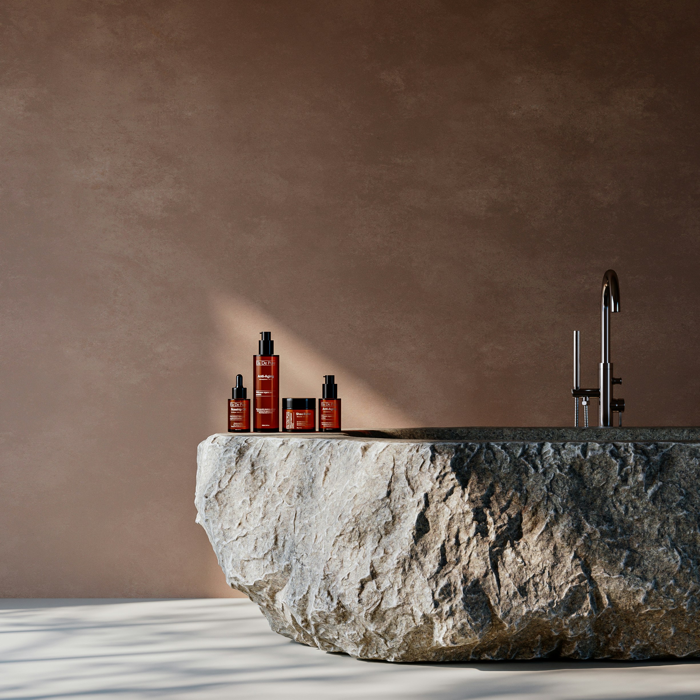 Four amber skincare bottles on a rough stone basin against a brown wall