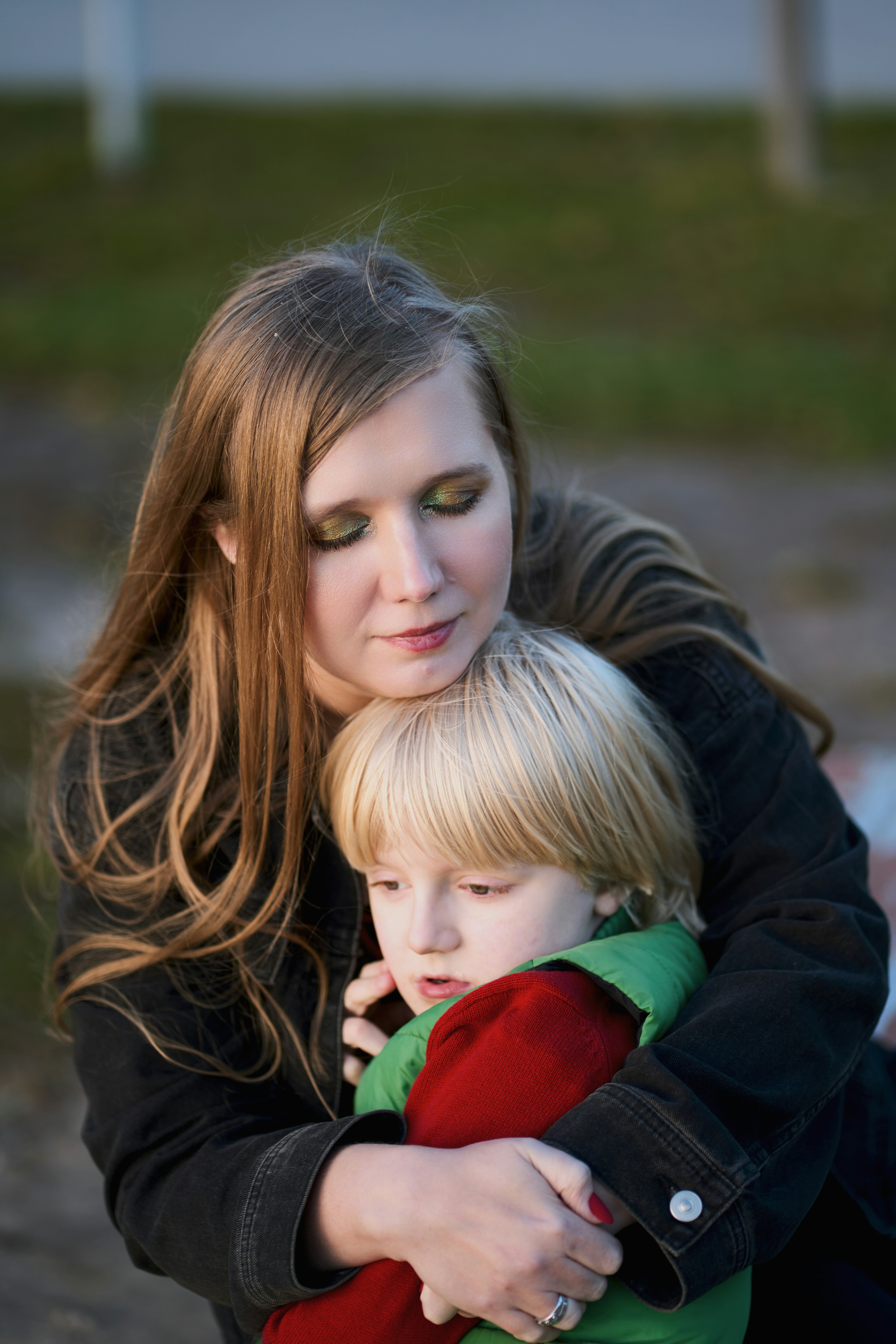A woman in a black jacket embracing a young child in a red sweater