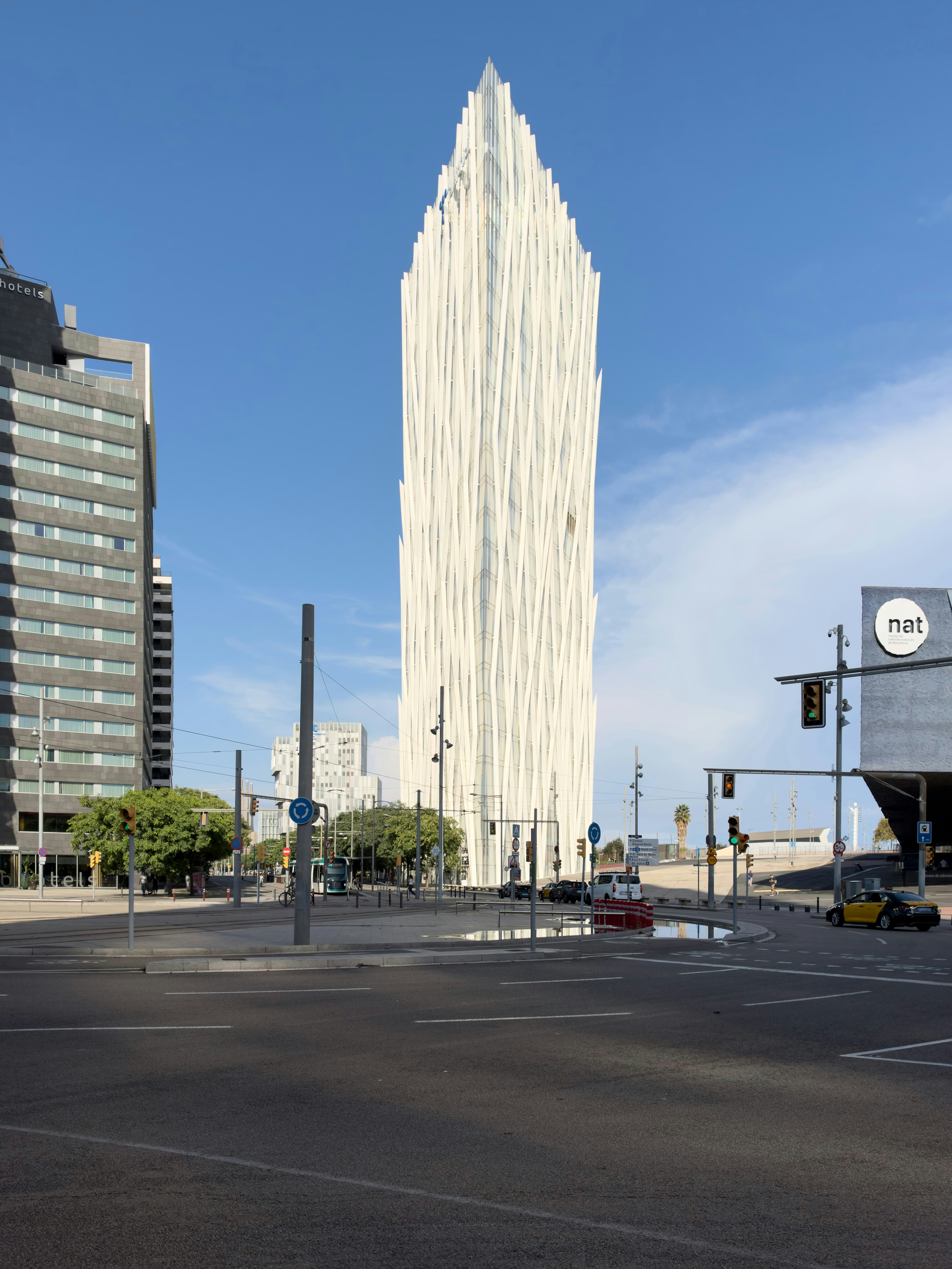 The white Torre Glòries skyscraper rising above a street intersection in Barcelona