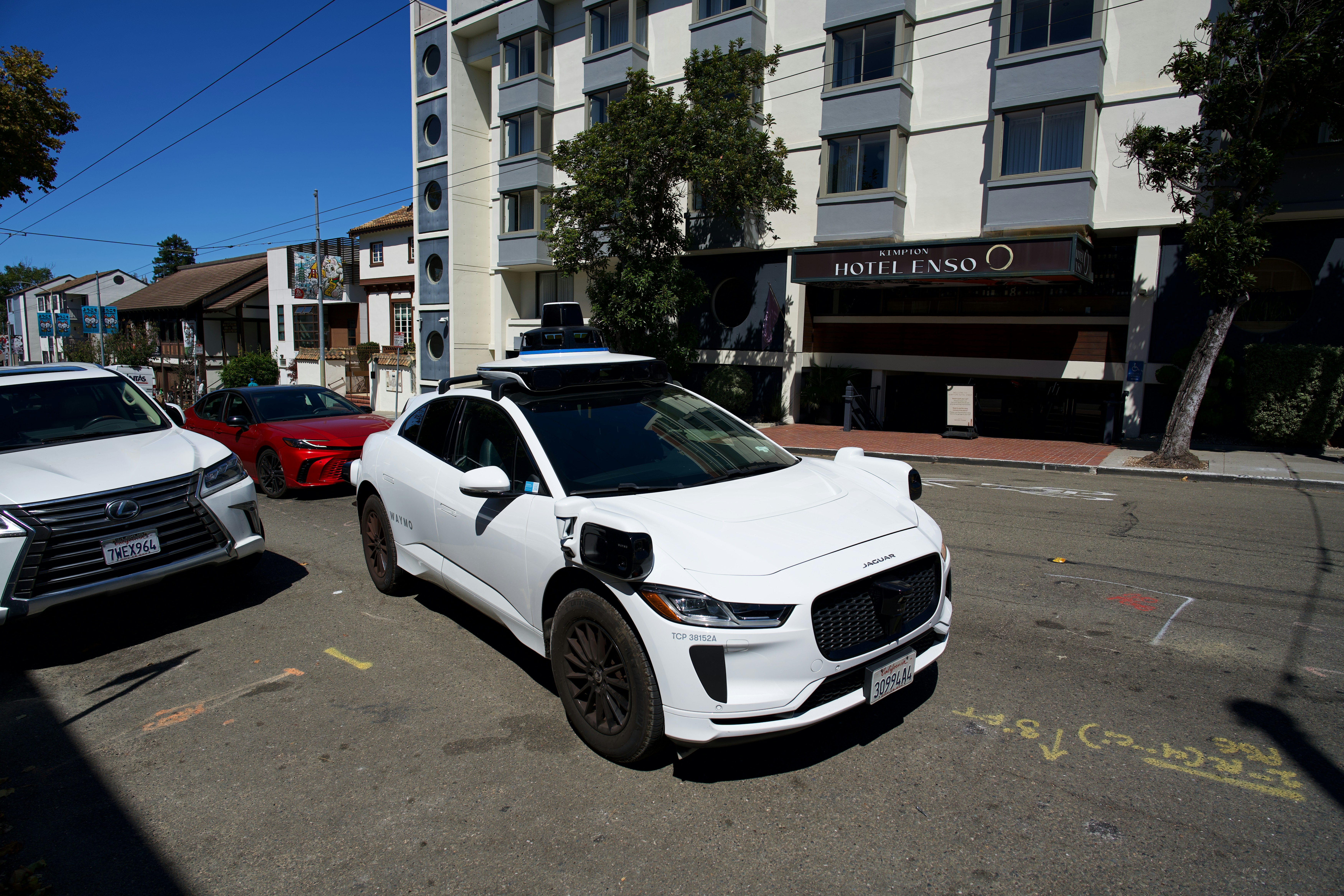 Um veículo Jaguar autônomo branco com sensores no teto estacionado do lado de fora do Hotel Enso
