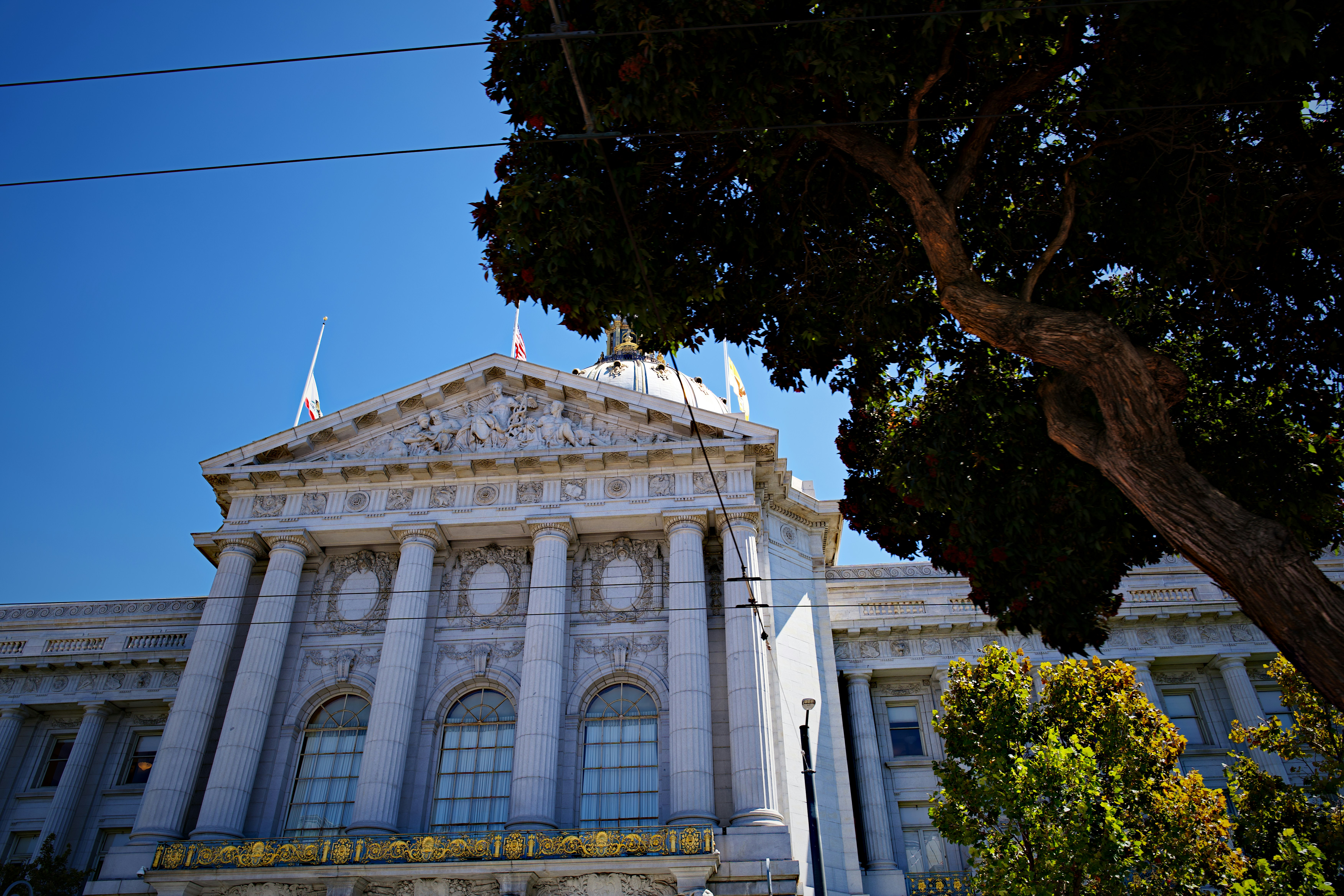 The San Francisco City Hall building with neoclassical columns under a clear blue sky