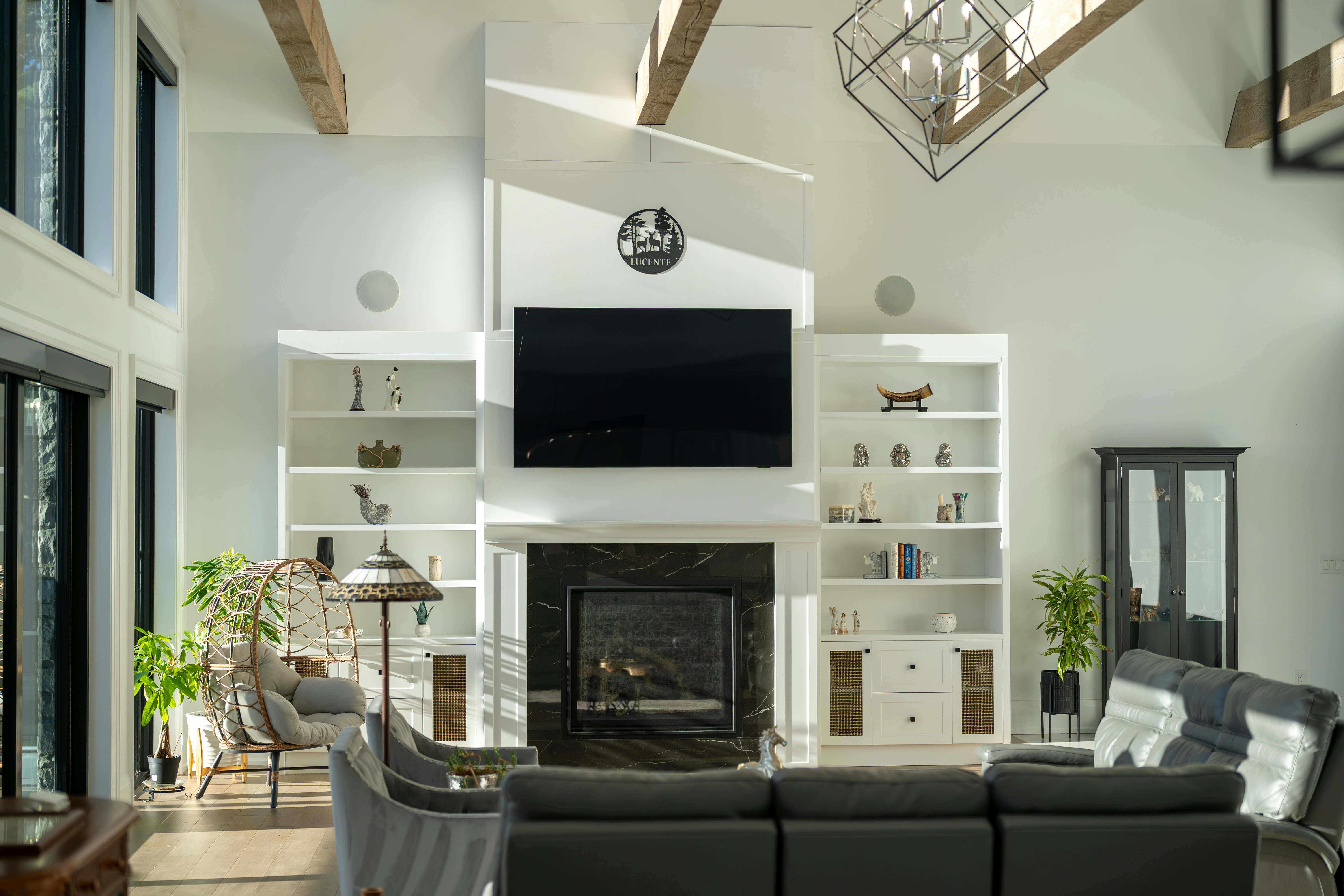 A living room with a black marble fireplace, white built-in shelves, and a grey leather sofa