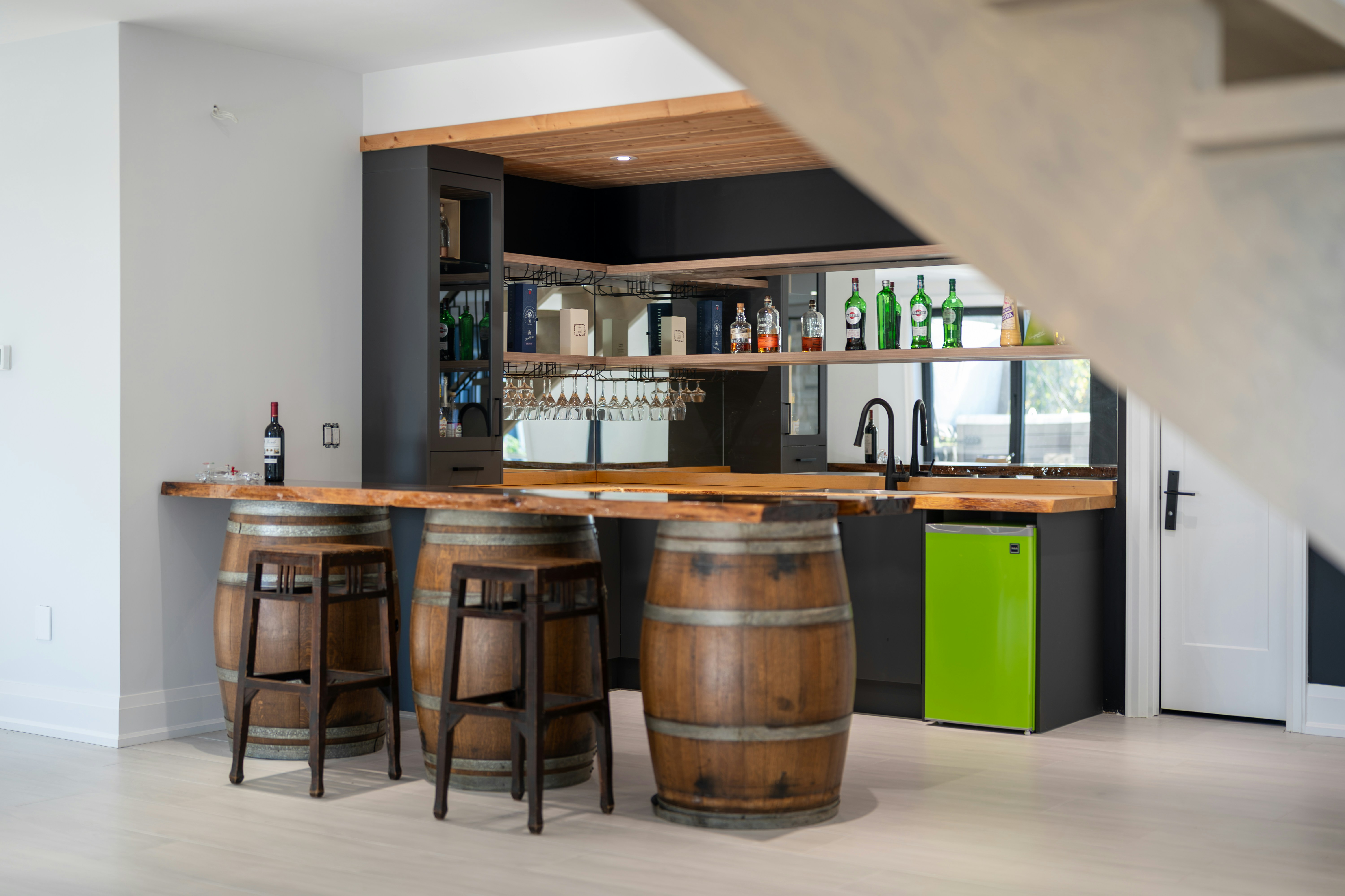 A home bar with wooden barrel stools and a live edge counter in a modern kitchen