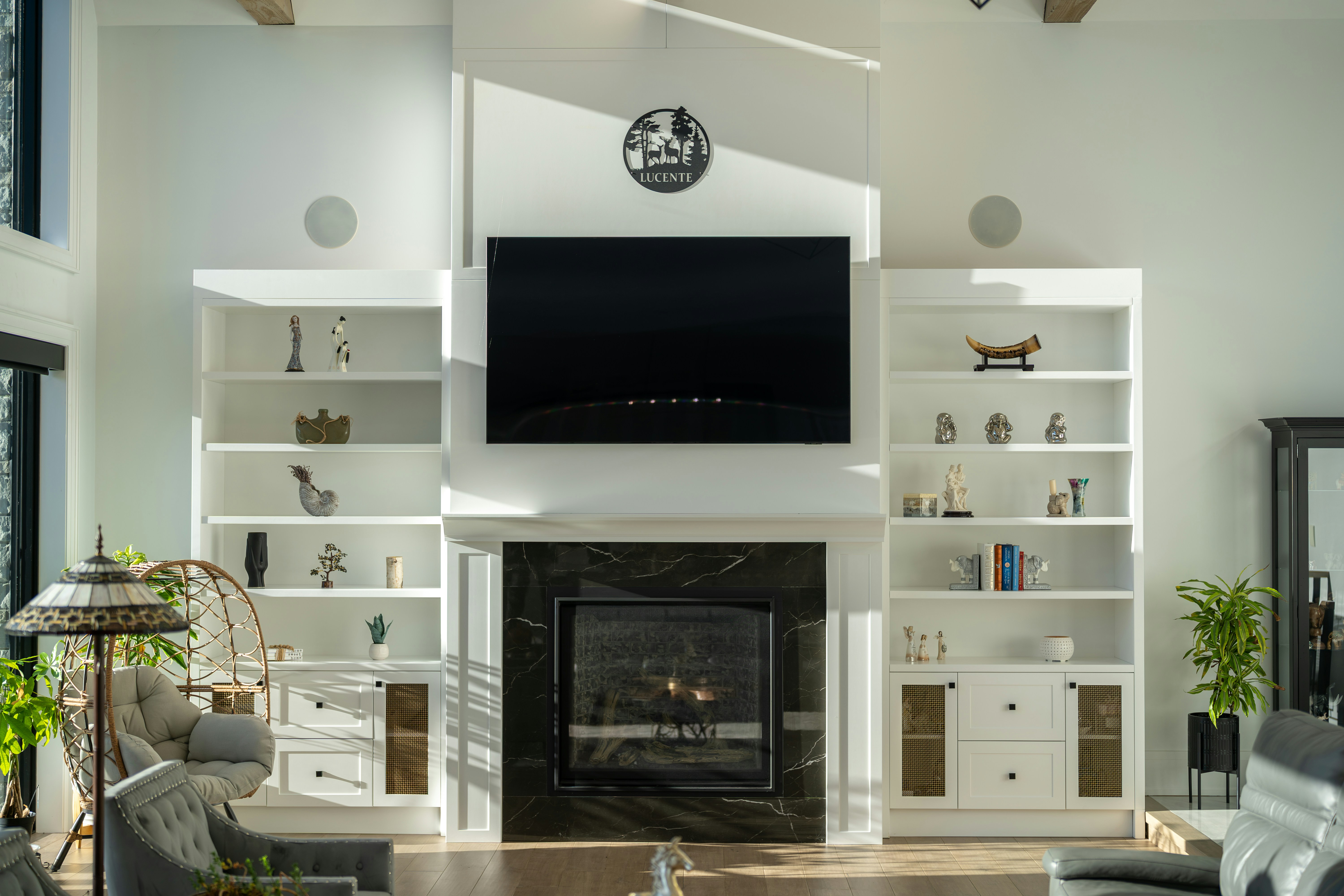 A fireplace with a black marble surround and a television mounted above in a bright living room