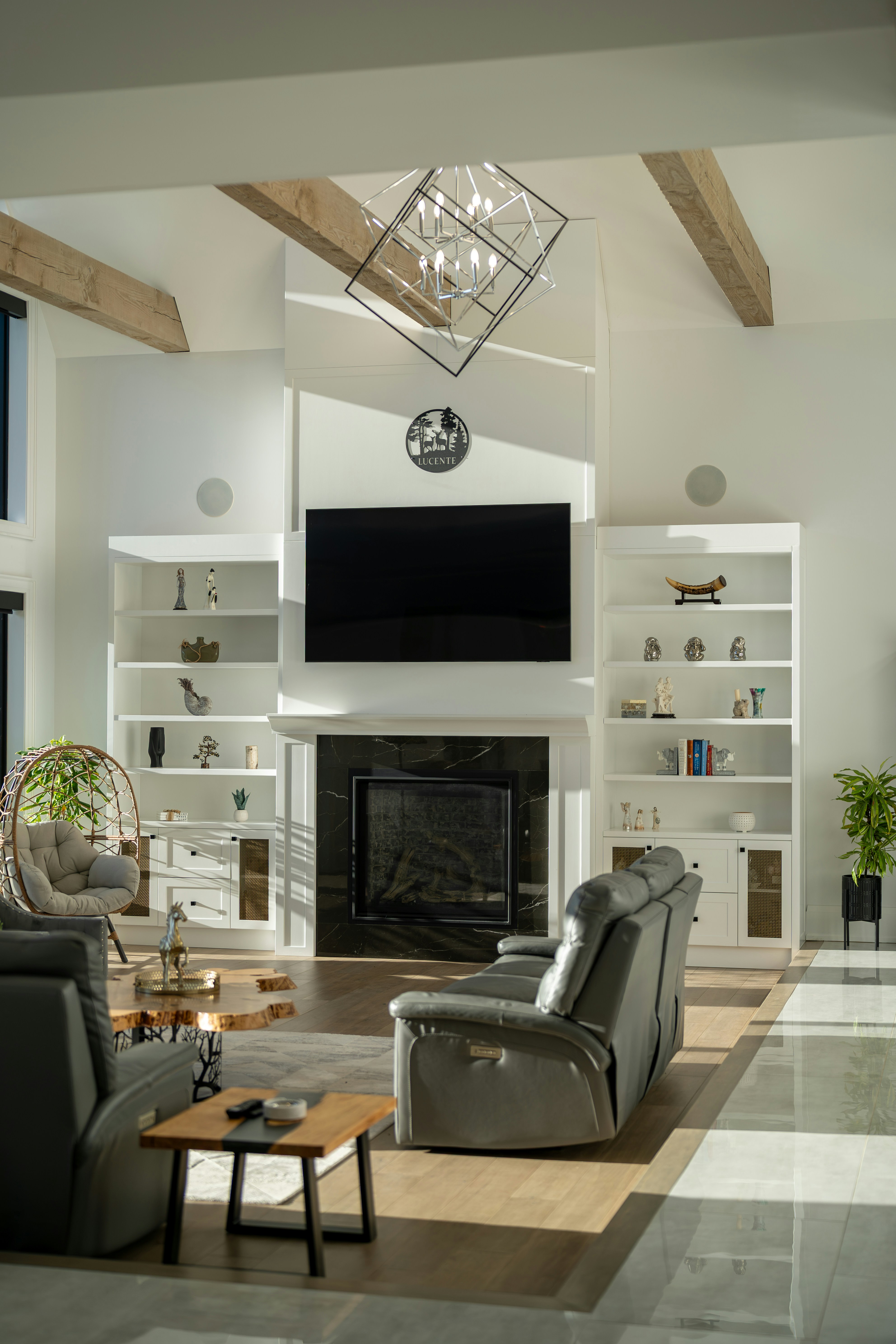 A living room with a black marble fireplace, white built-in shelves, and grey leather recliners