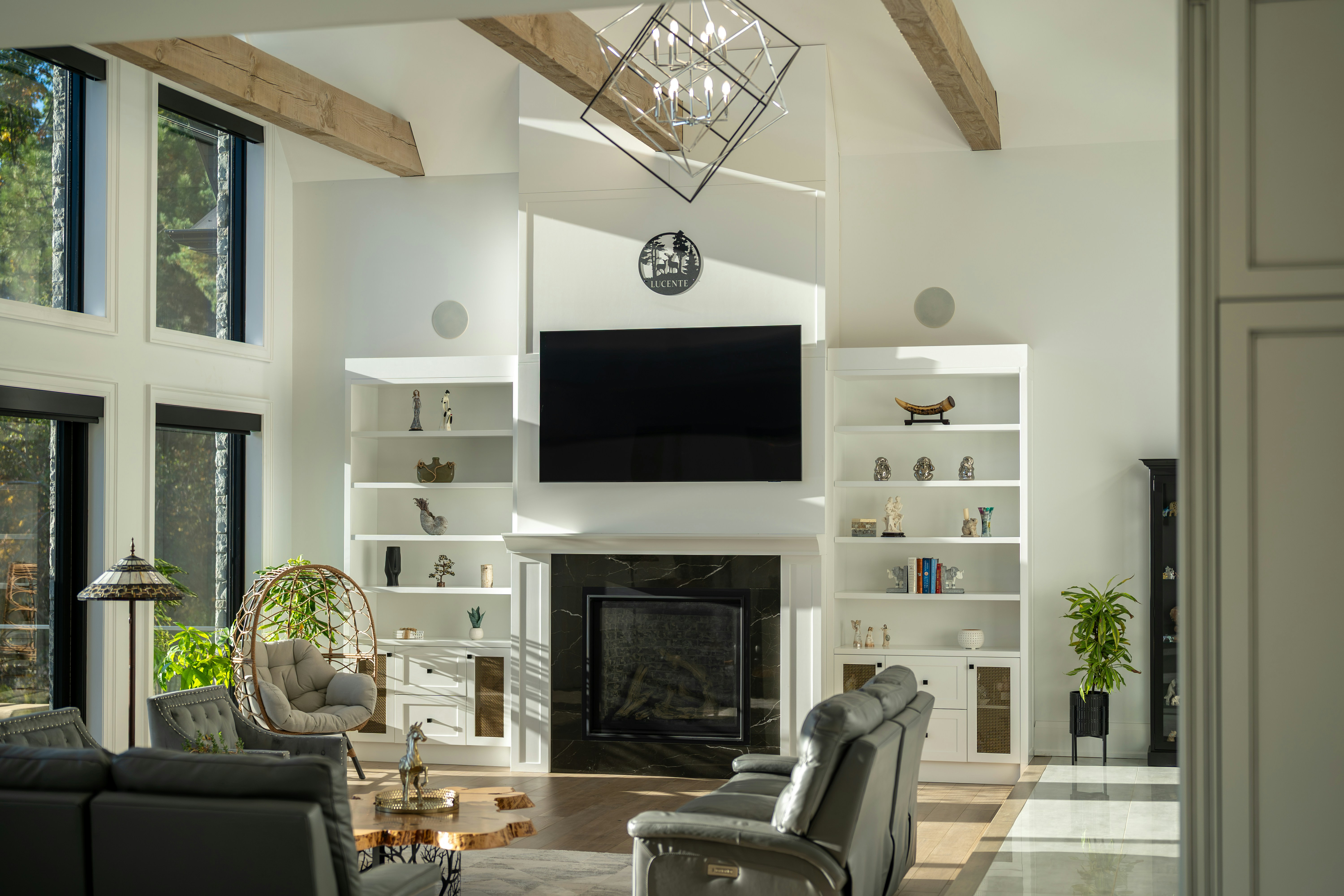 A living room with a black fireplace, built-in white shelves, and grey leather furniture