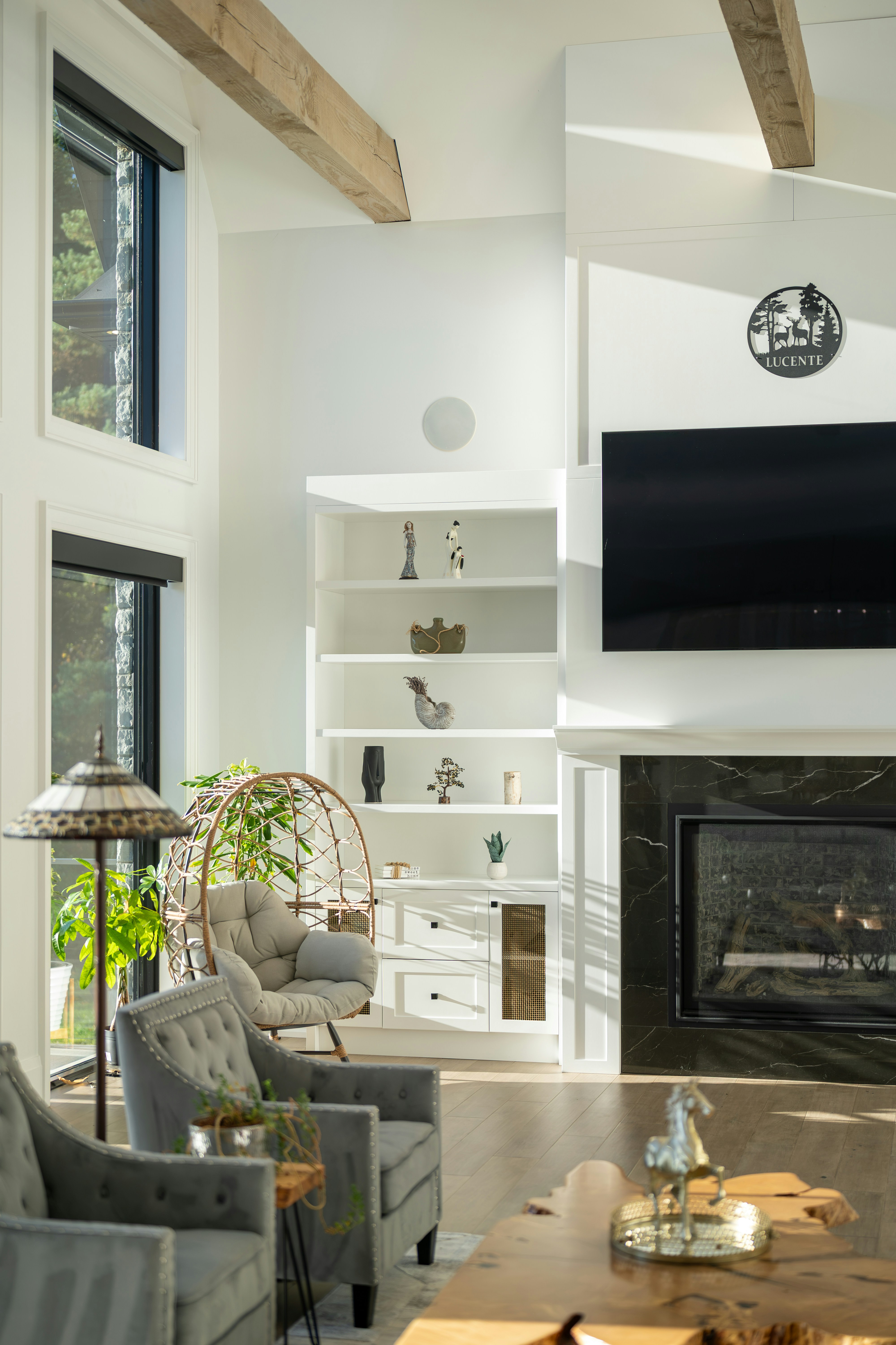 A sunlit living room with a fireplace, a hanging chair, and grey armchairs