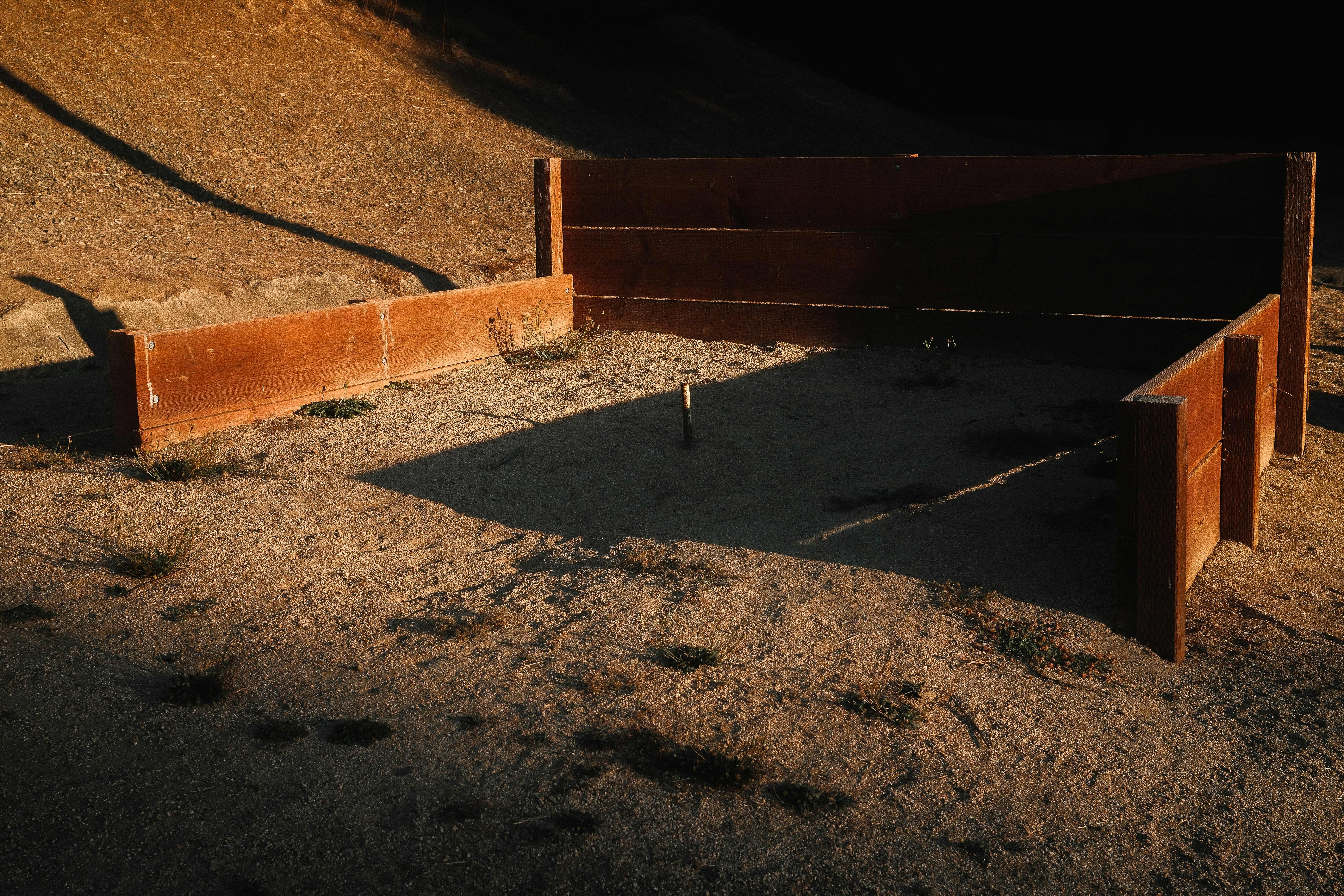 A horseshoe pit with wooden boards and a metal stake in sandy ground