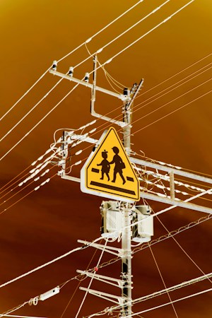 Yellow school crossing sign on a utility pole against an orange evening sky, as Clark County adds $715,557 a year for more school crossing guards