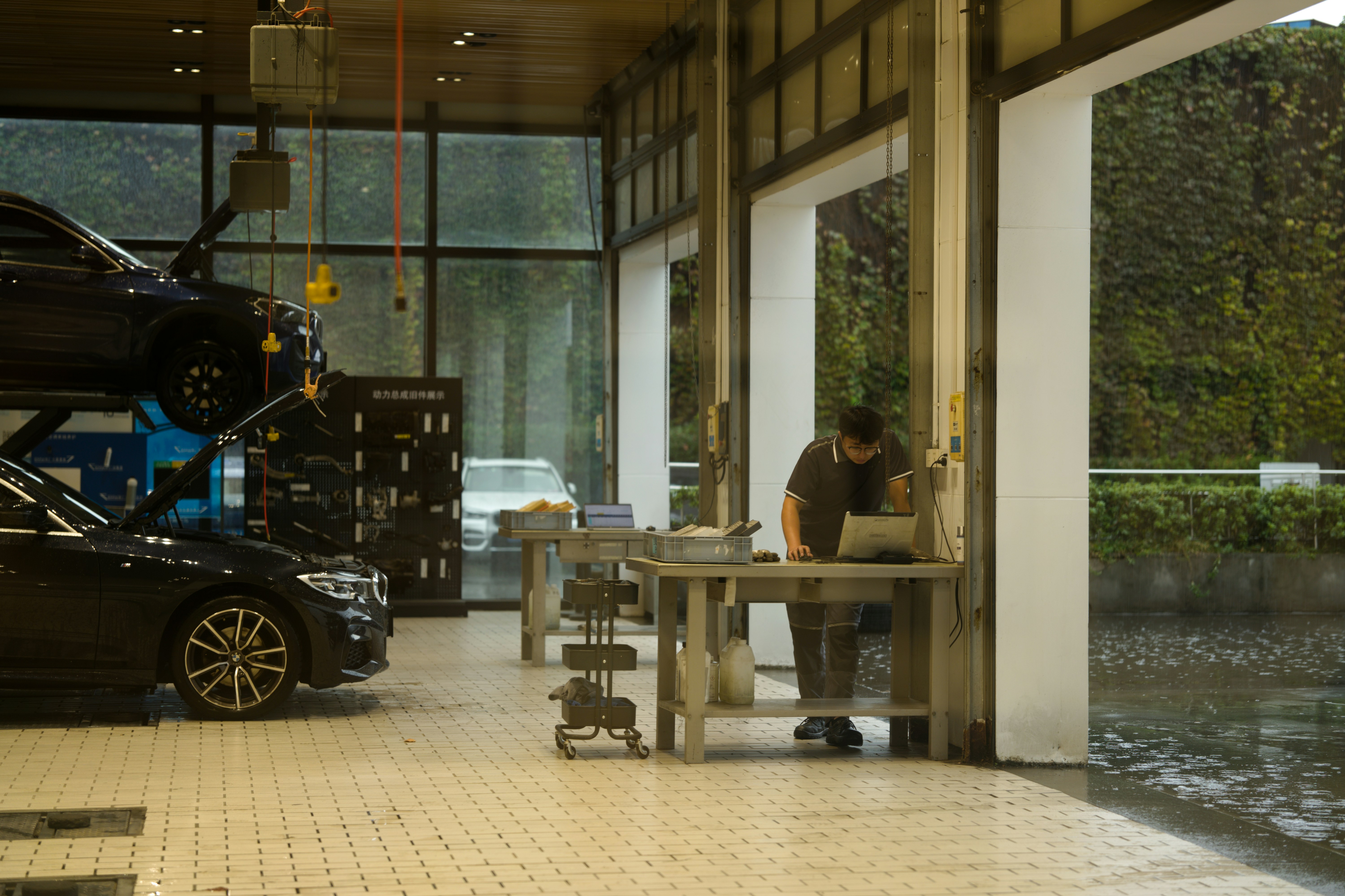 A mechanic using a laptop at a workbench in a car repair shop