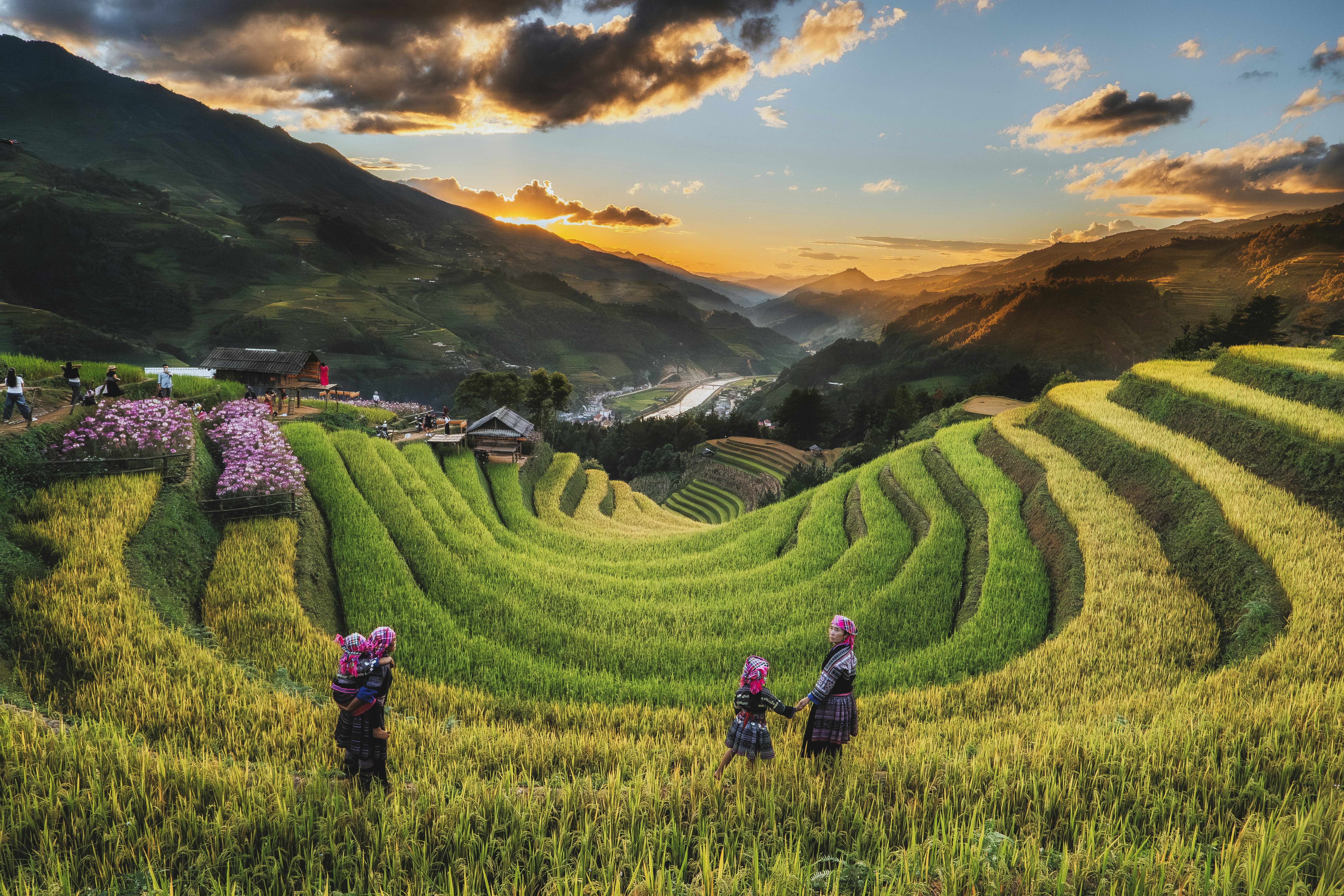 Menschen in traditioneller Kleidung, die durch terrassierte Reisfelder in Mu Cang Chai, Vietnam, spazieren gehen