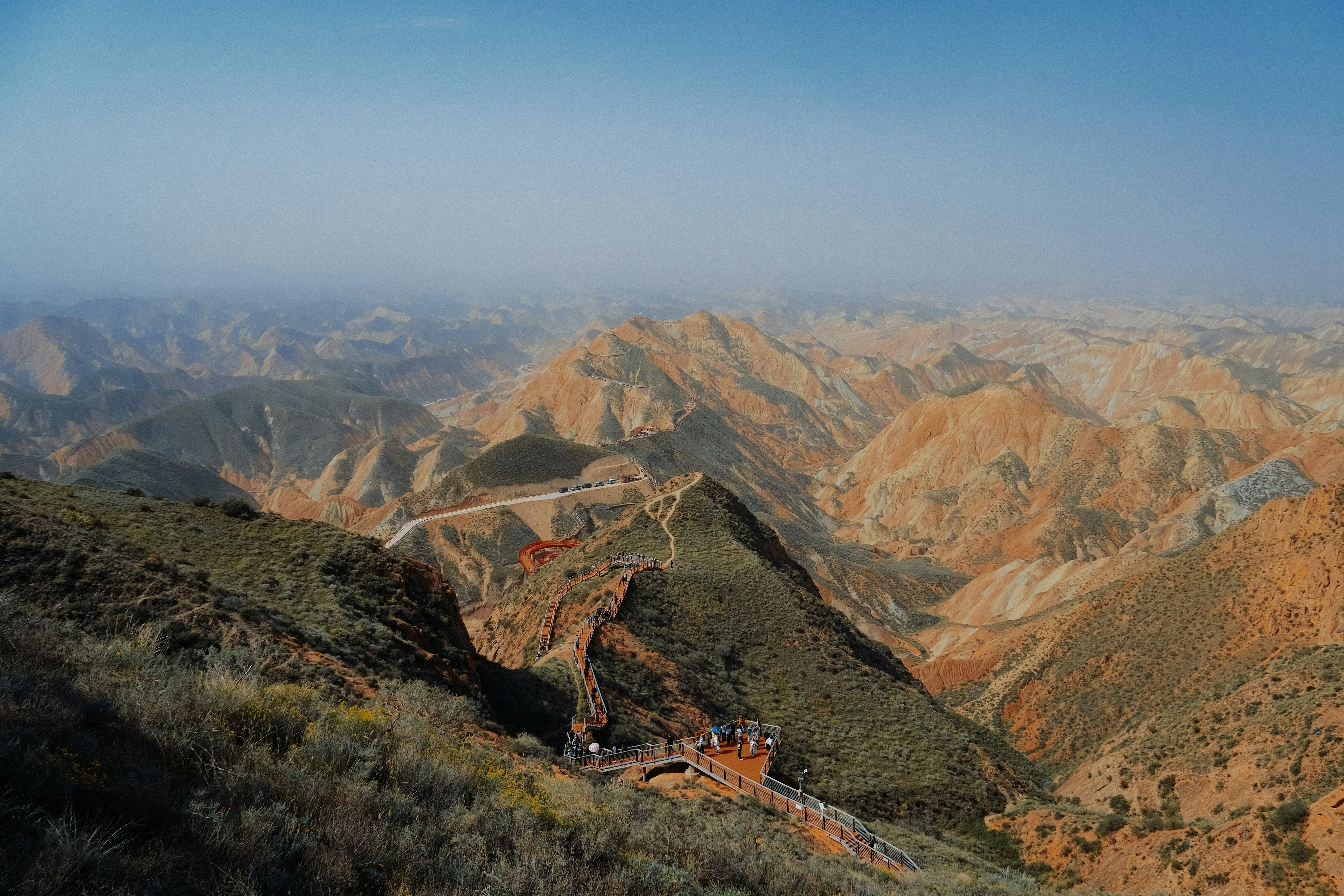 A wooden walkway winding through colorful eroded mountains in Zhangye Danxia National Geological Park