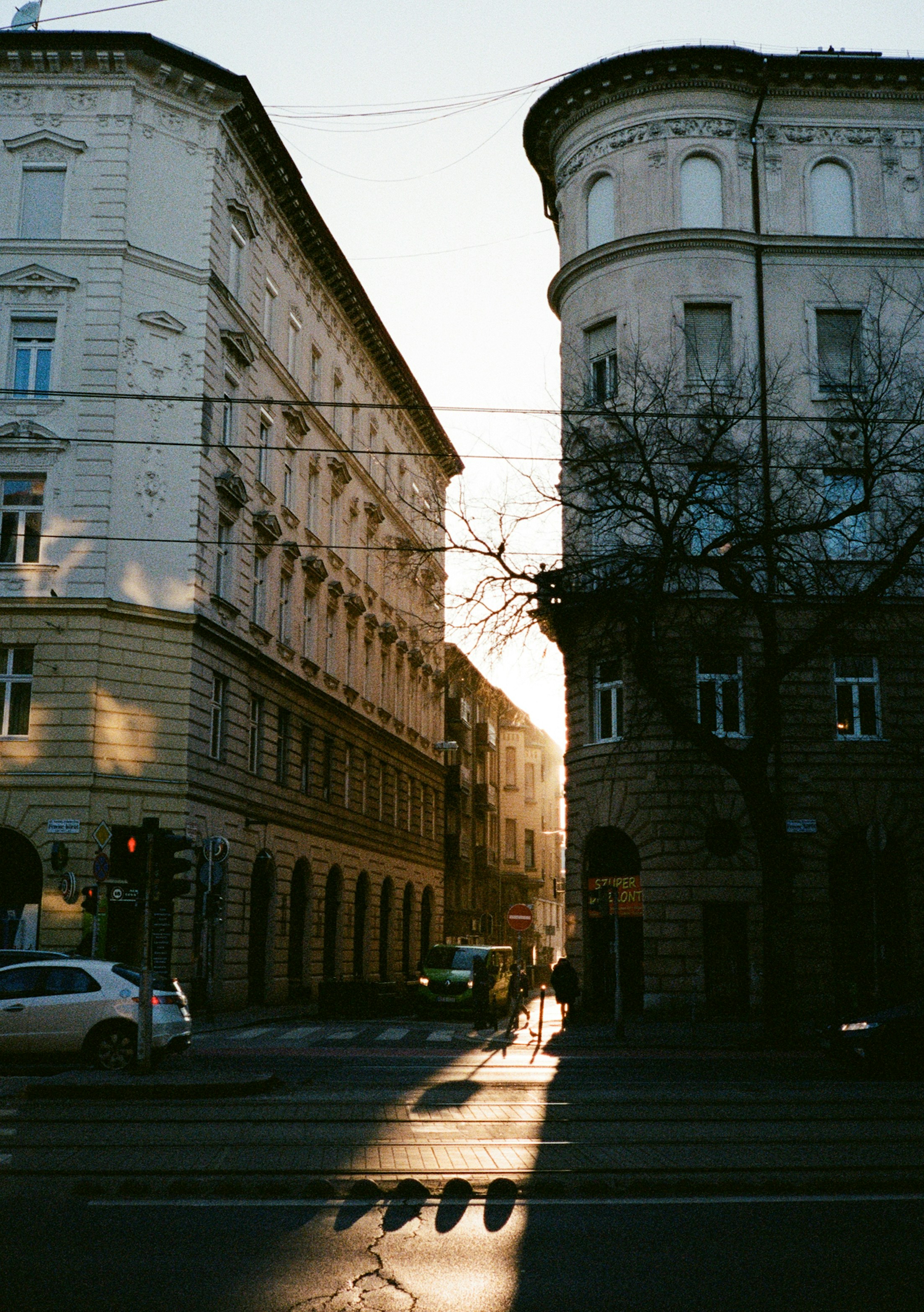 Eine schmale Straße zwischen hohen historischen Gebäuden in Budapest, in der die niedrige Sonne lange Schatten wirft