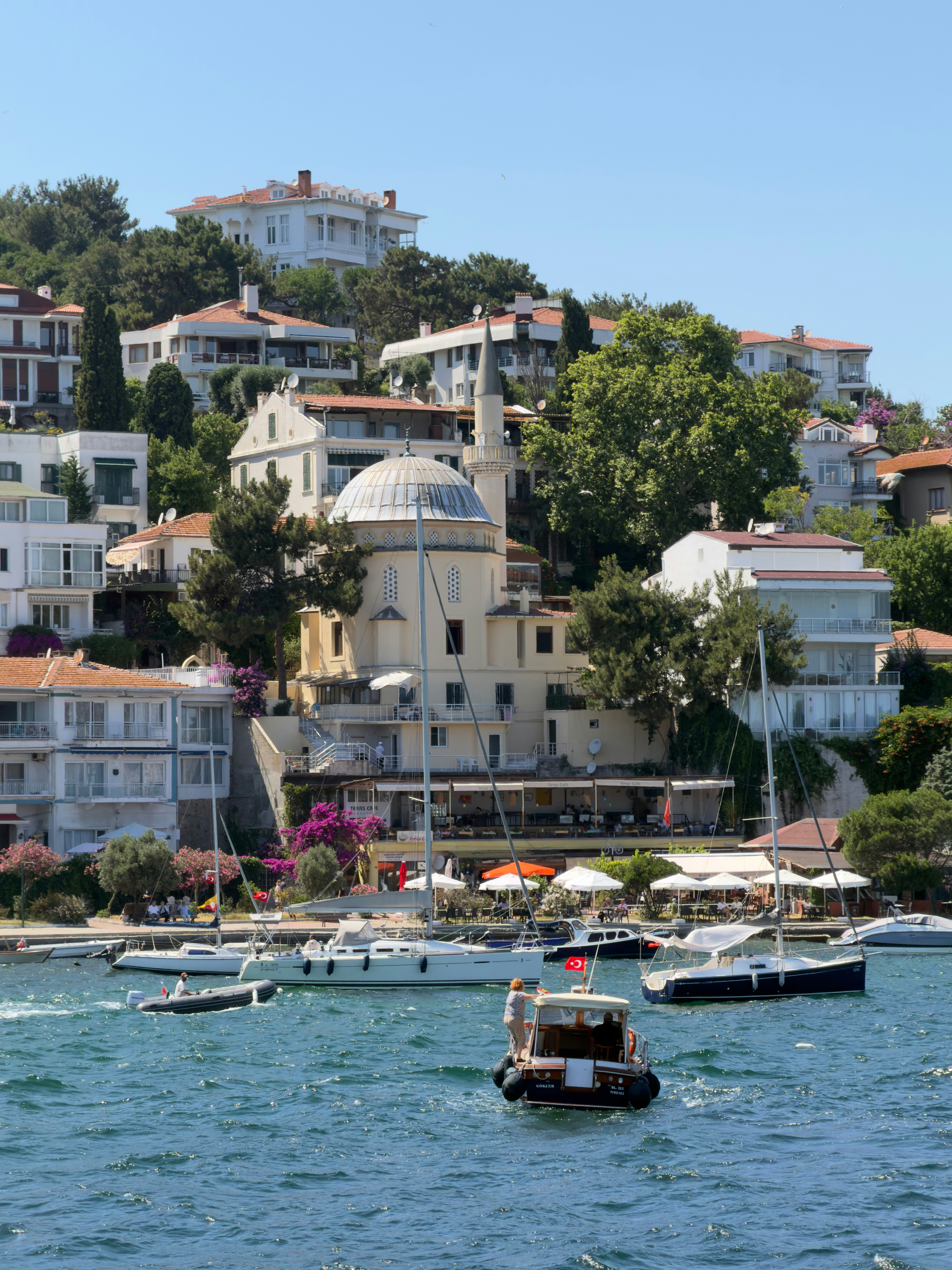 A mosque with a dome and minaret on a hillside overlooking a harbor in Istanbul
