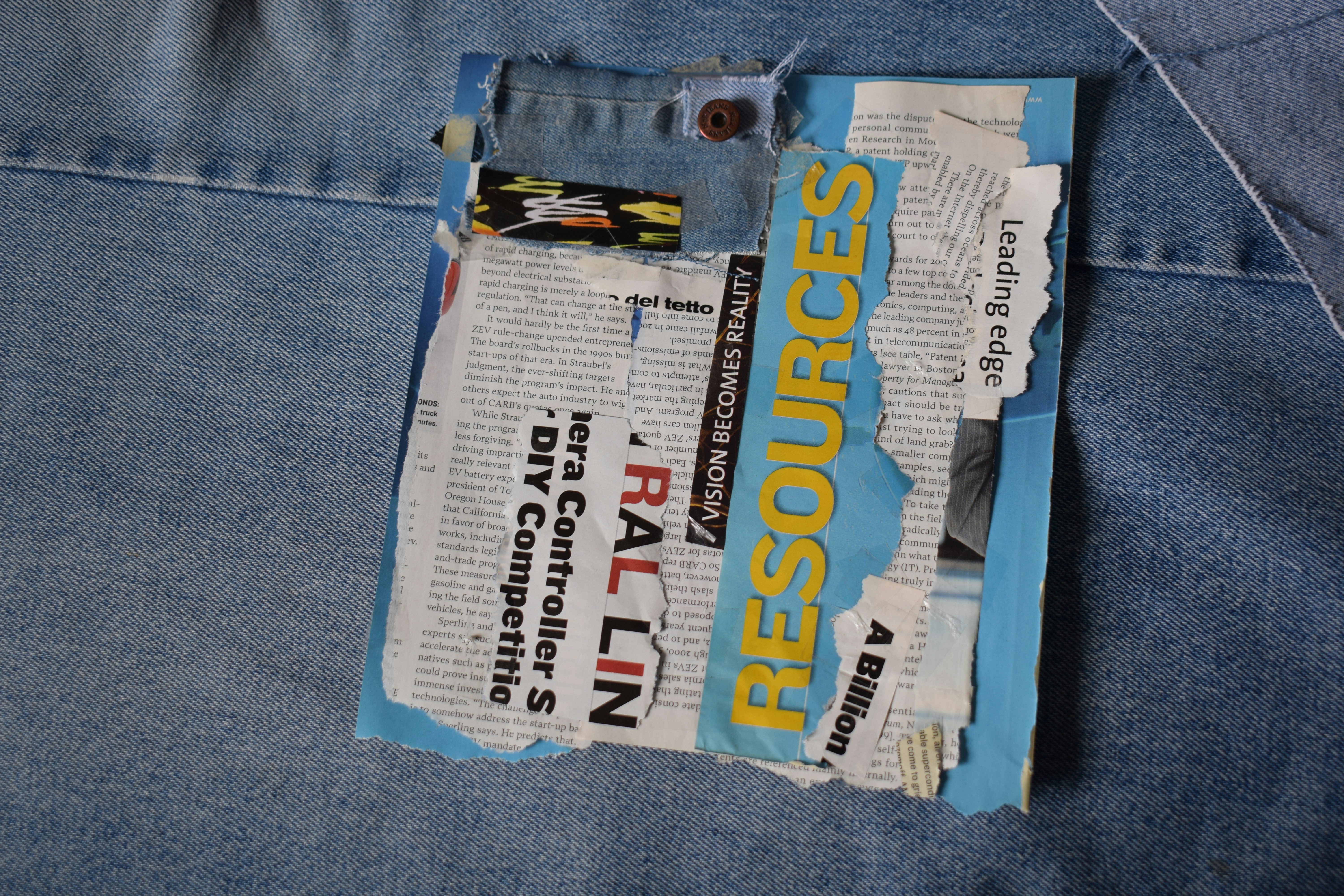 A collage of torn paper scraps and text on a light blue denim background