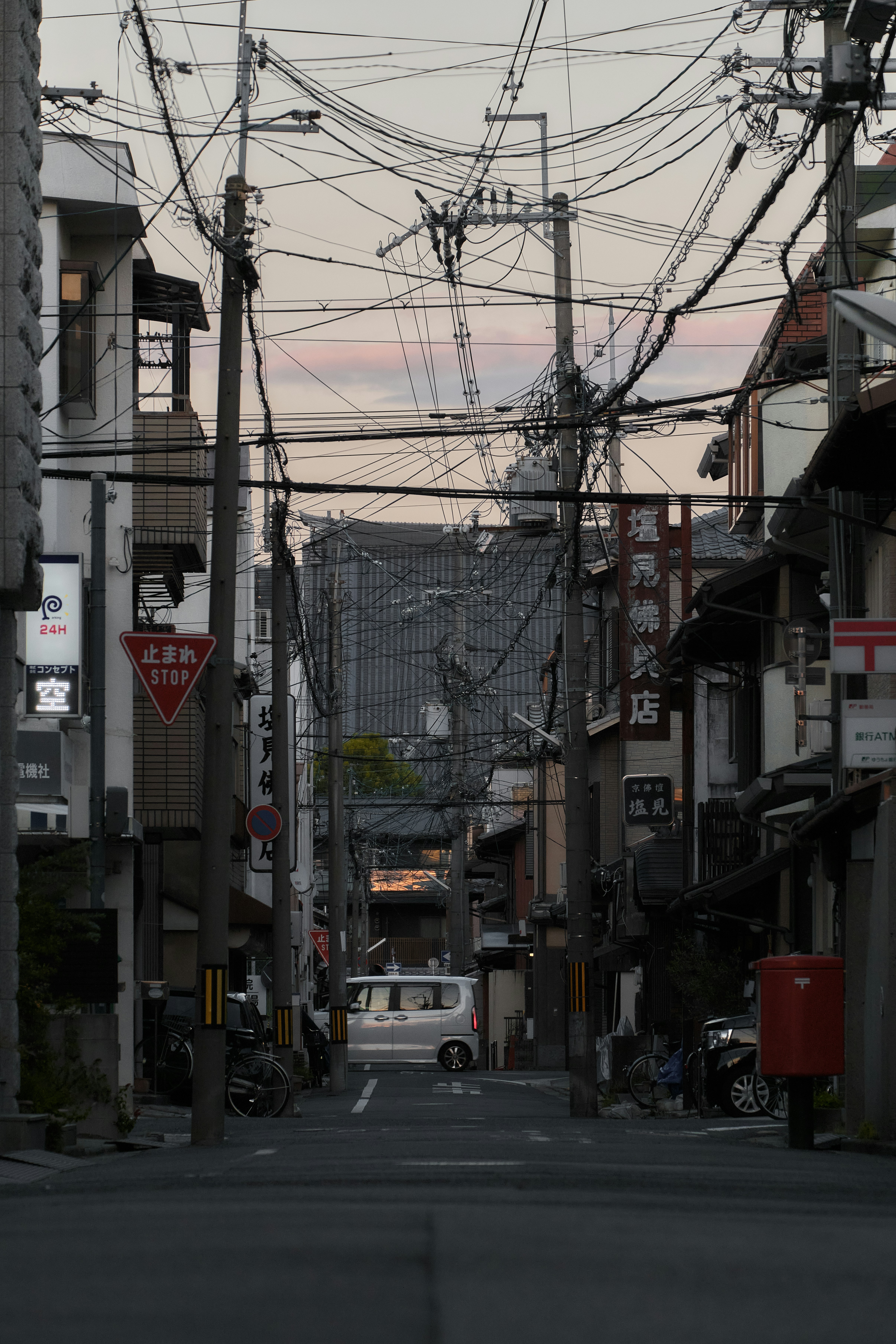 Une rue étroite à Kyoto avec des lignes électriques aériennes denses et des bâtiments traditionnels au crépuscule