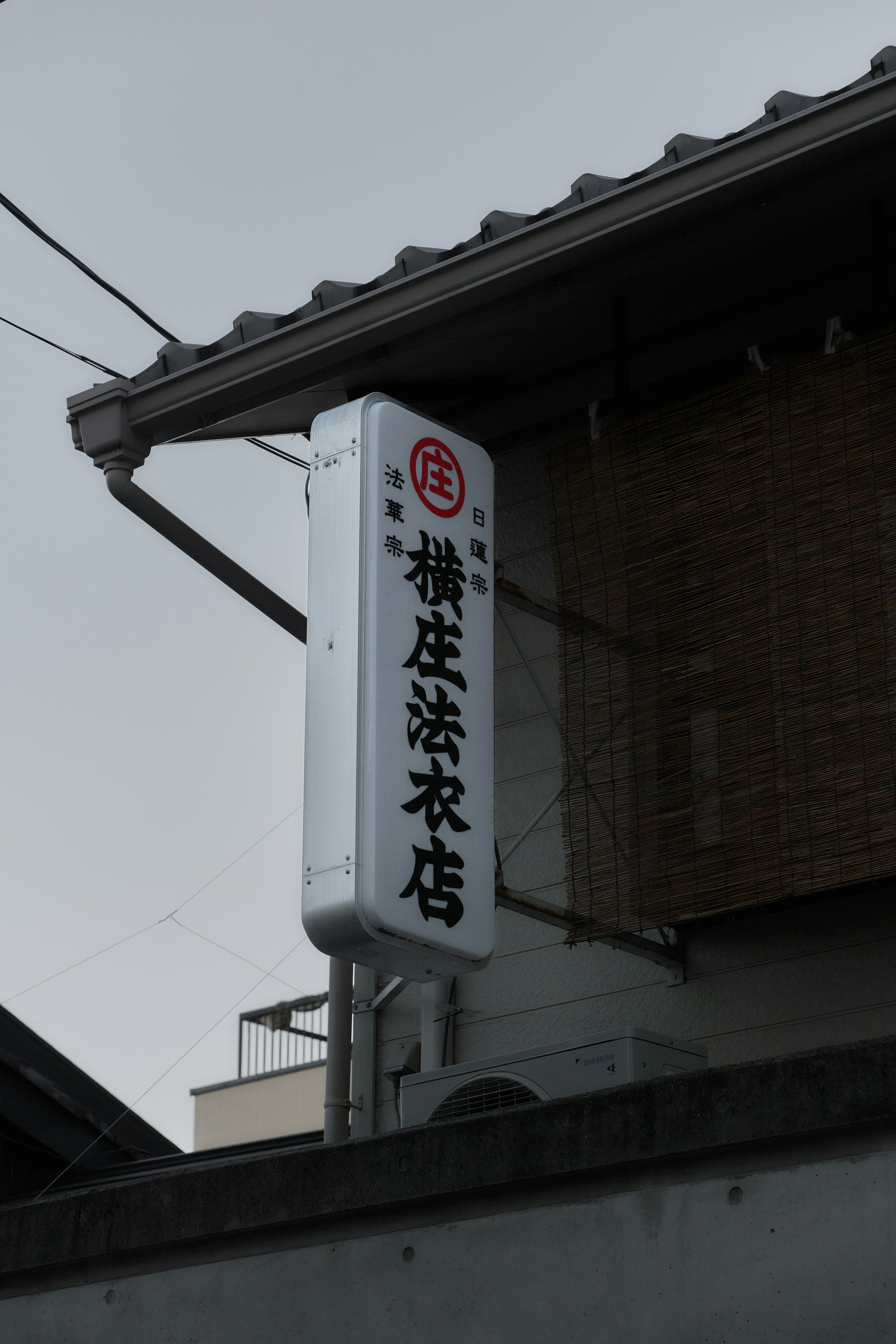 Un panneau vertical illuminé avec des caractères japonais suspendu à un bâtiment à Kyoto