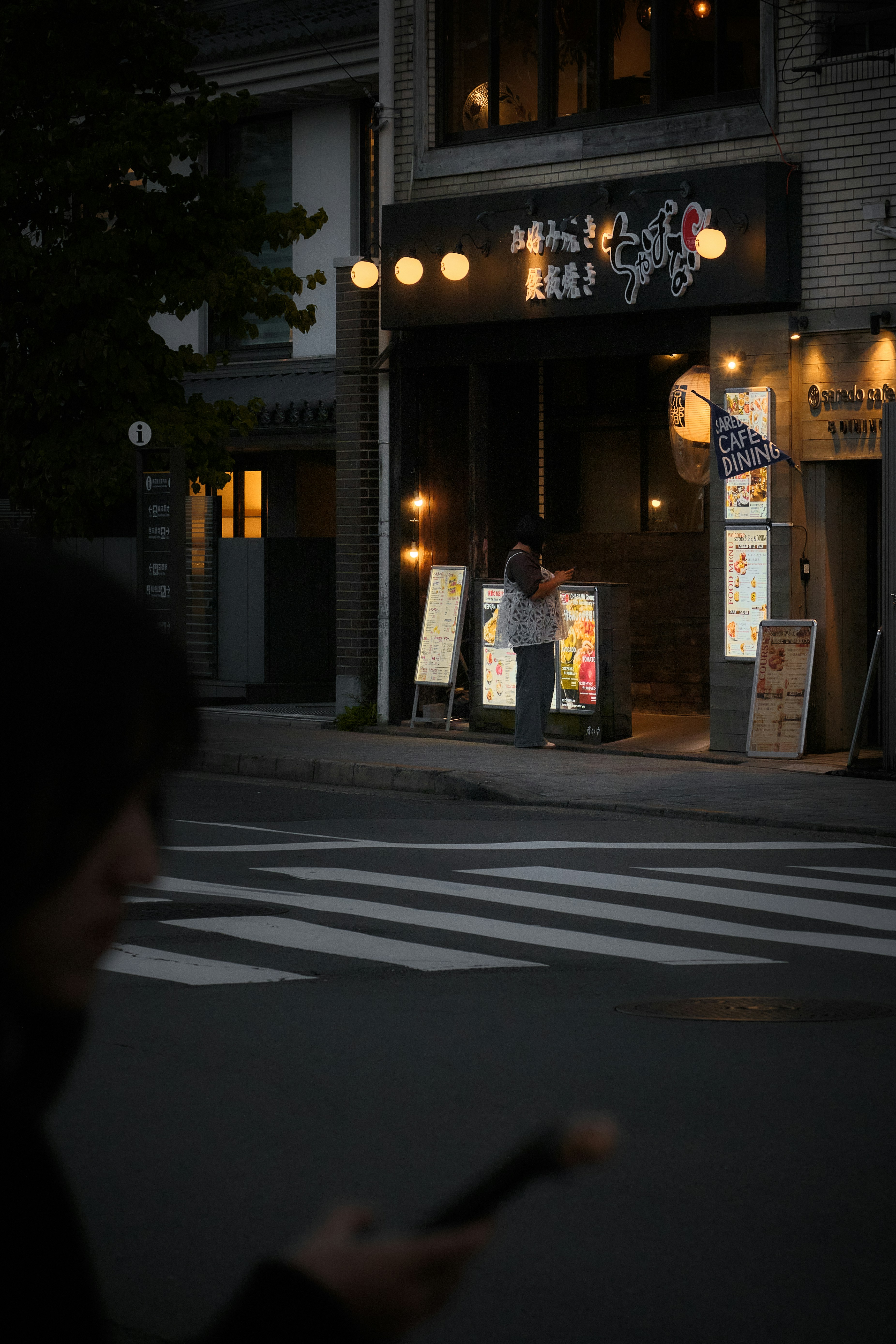 Une personne utilisant un téléphone devant un restaurant la nuit à Kyoto, Japon