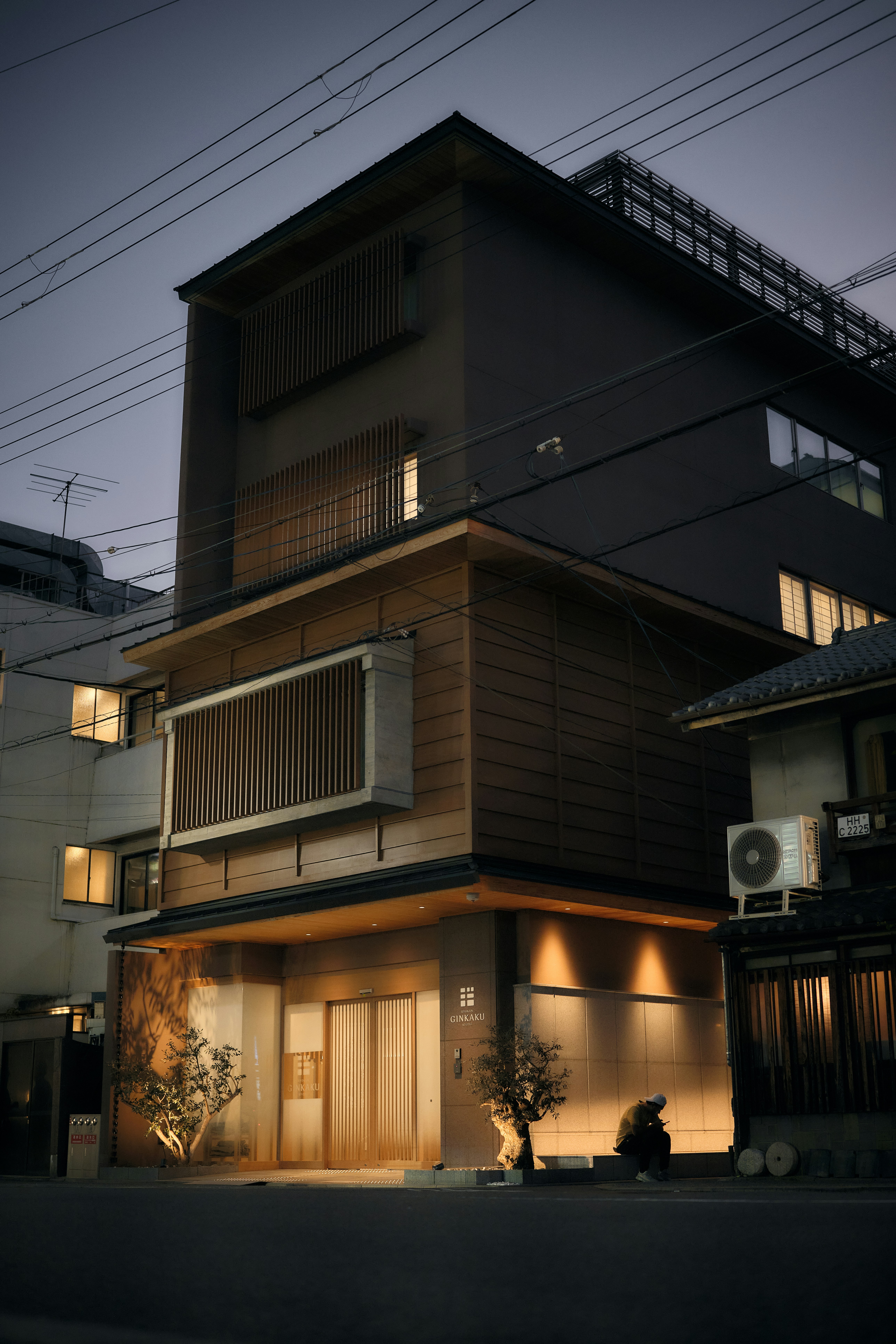 A person sitting on a step outside the Ginkaku hotel in Kyoto at dusk