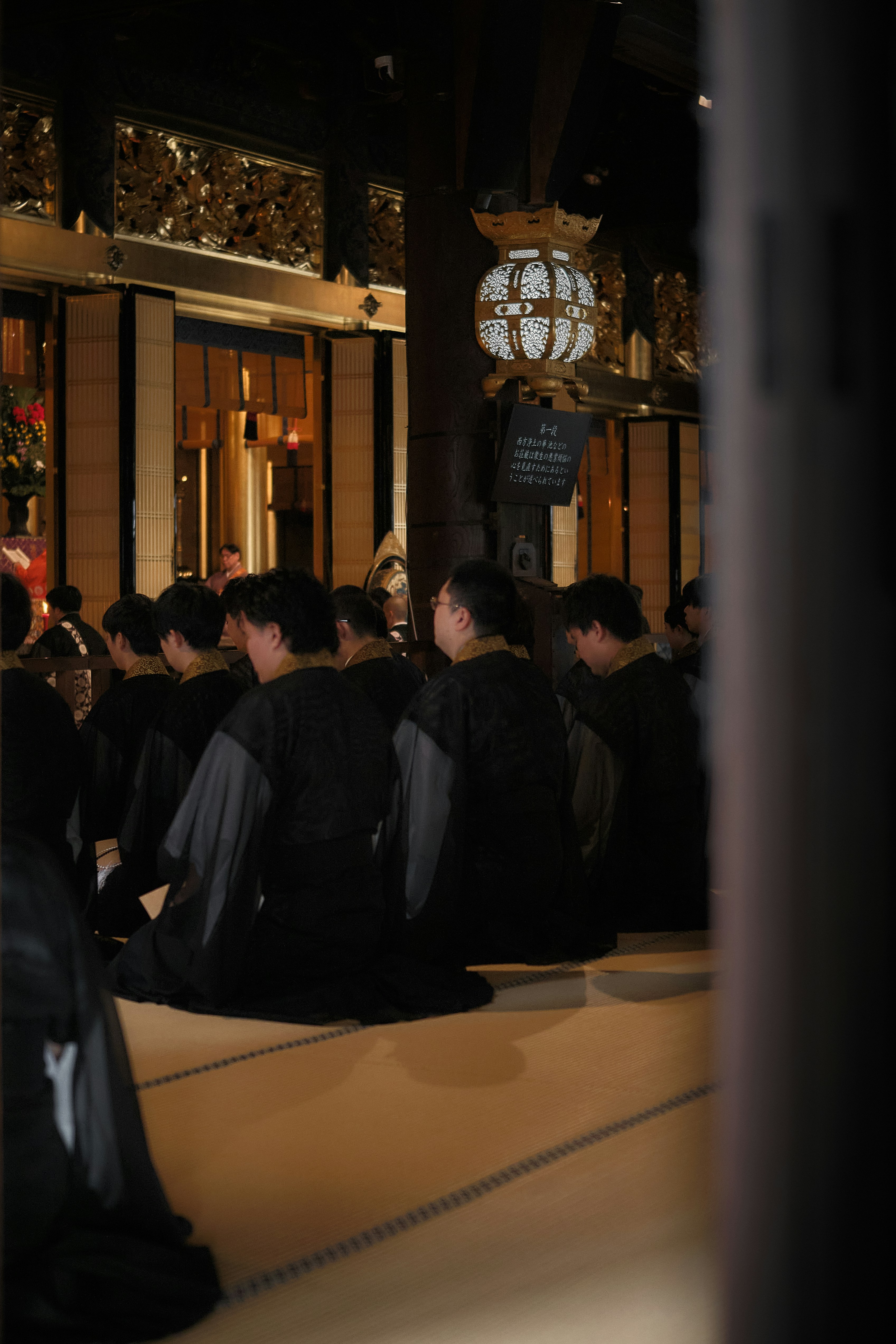 Des gens en robes noires agenouillés sur des tatami à l’intérieur d’un temple à Kyoto