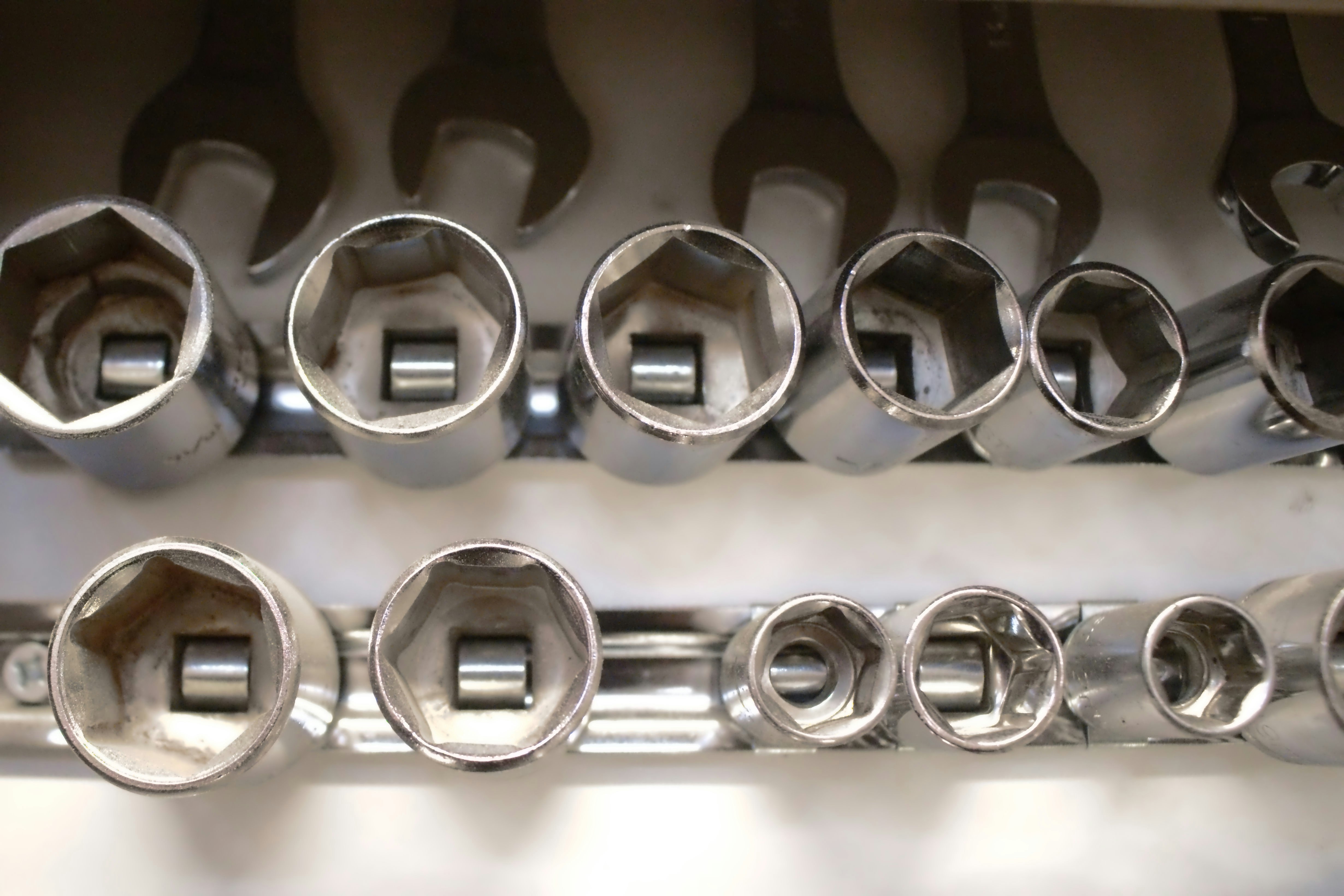 A collection of chrome socket wrench heads arranged in rows on metal rails