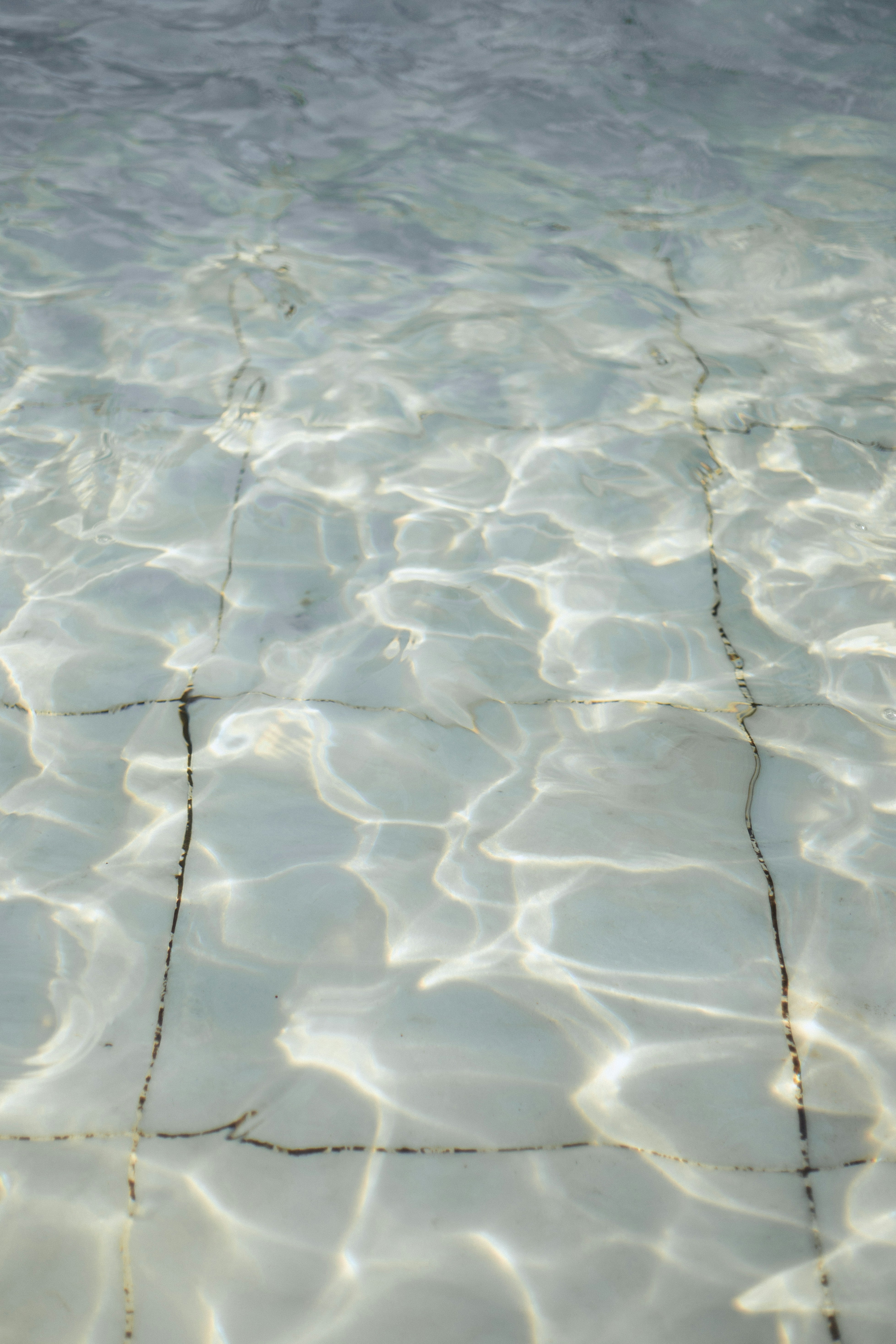 Sunlight reflecting on the clear water of a tiled swimming pool