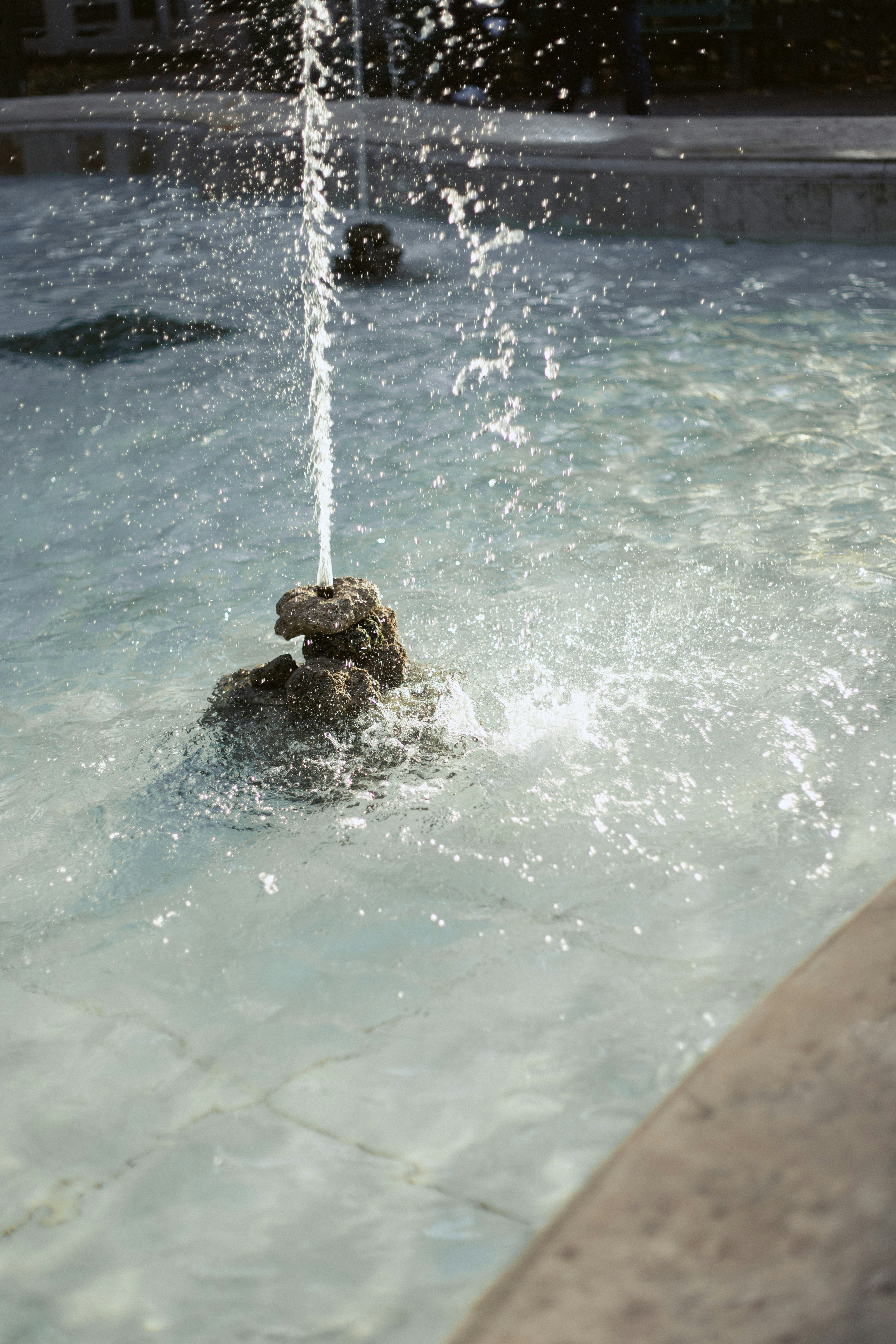 A water fountain spraying a thin stream of water over a small stone structure