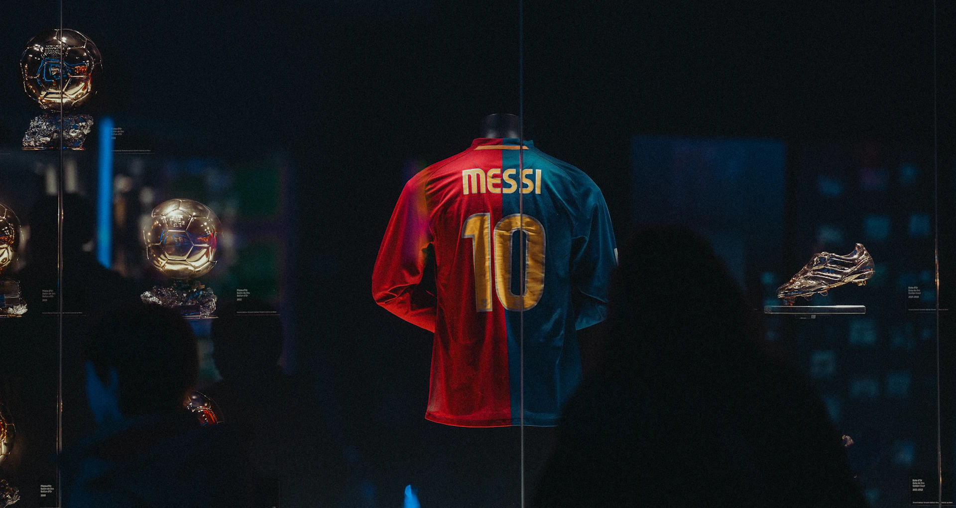 A Messi jersey with number ten displayed in a glass case with golden trophies