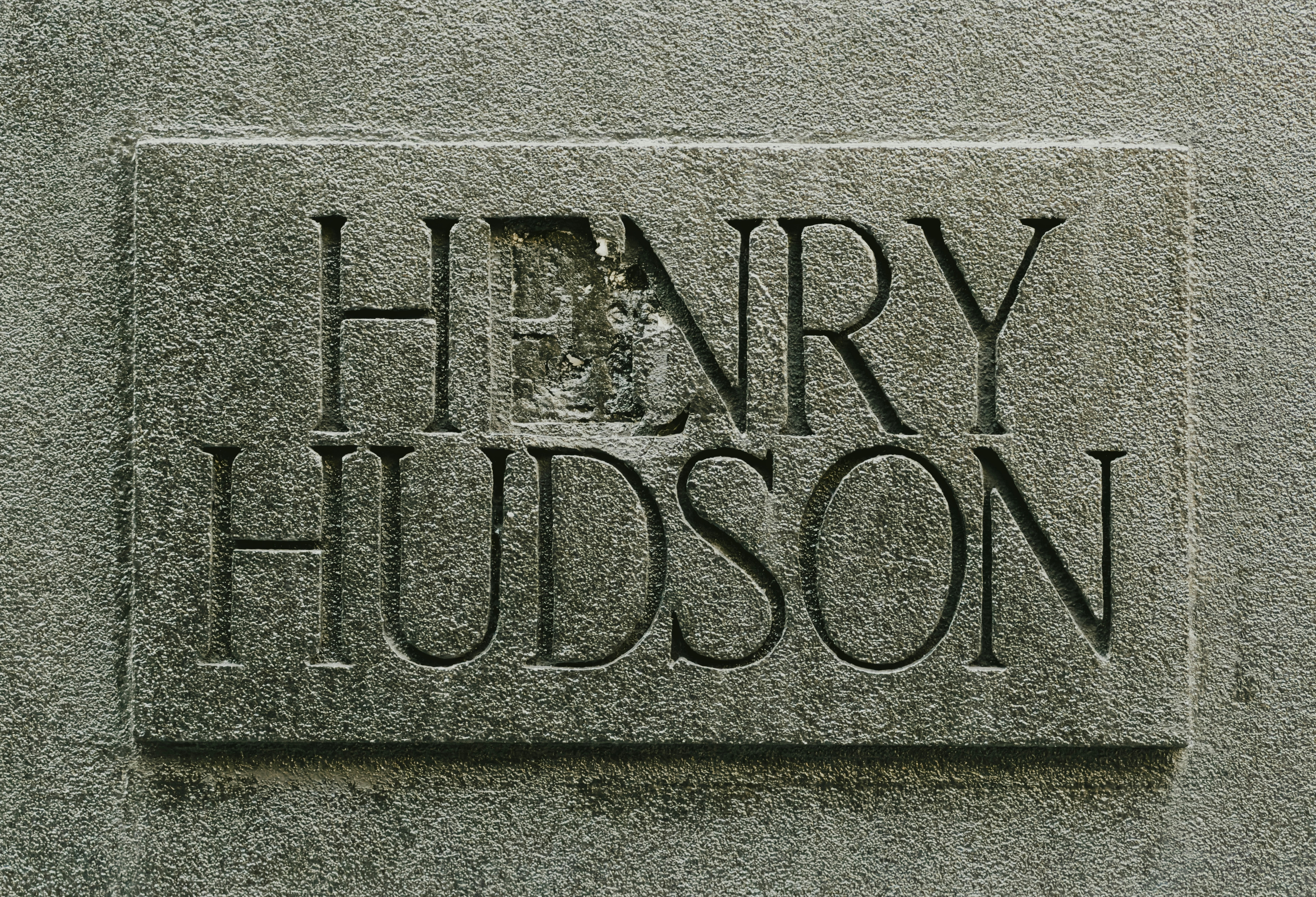 The name Henry Hudson carved into a textured grey stone plaque