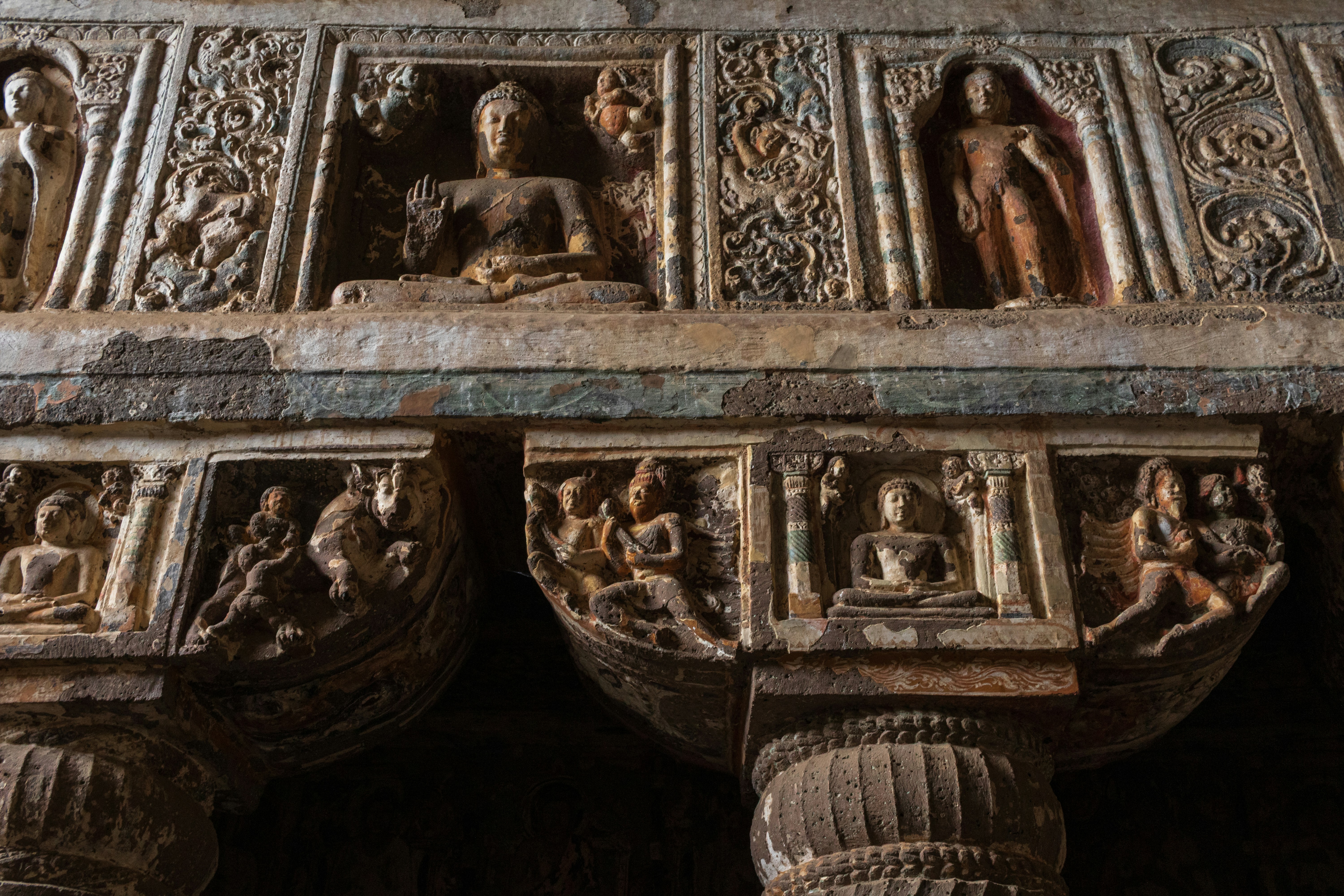 Rock-cut Buddha reliefs and ornate carvings on columns inside Cave 19 of the Ajanta Caves in India