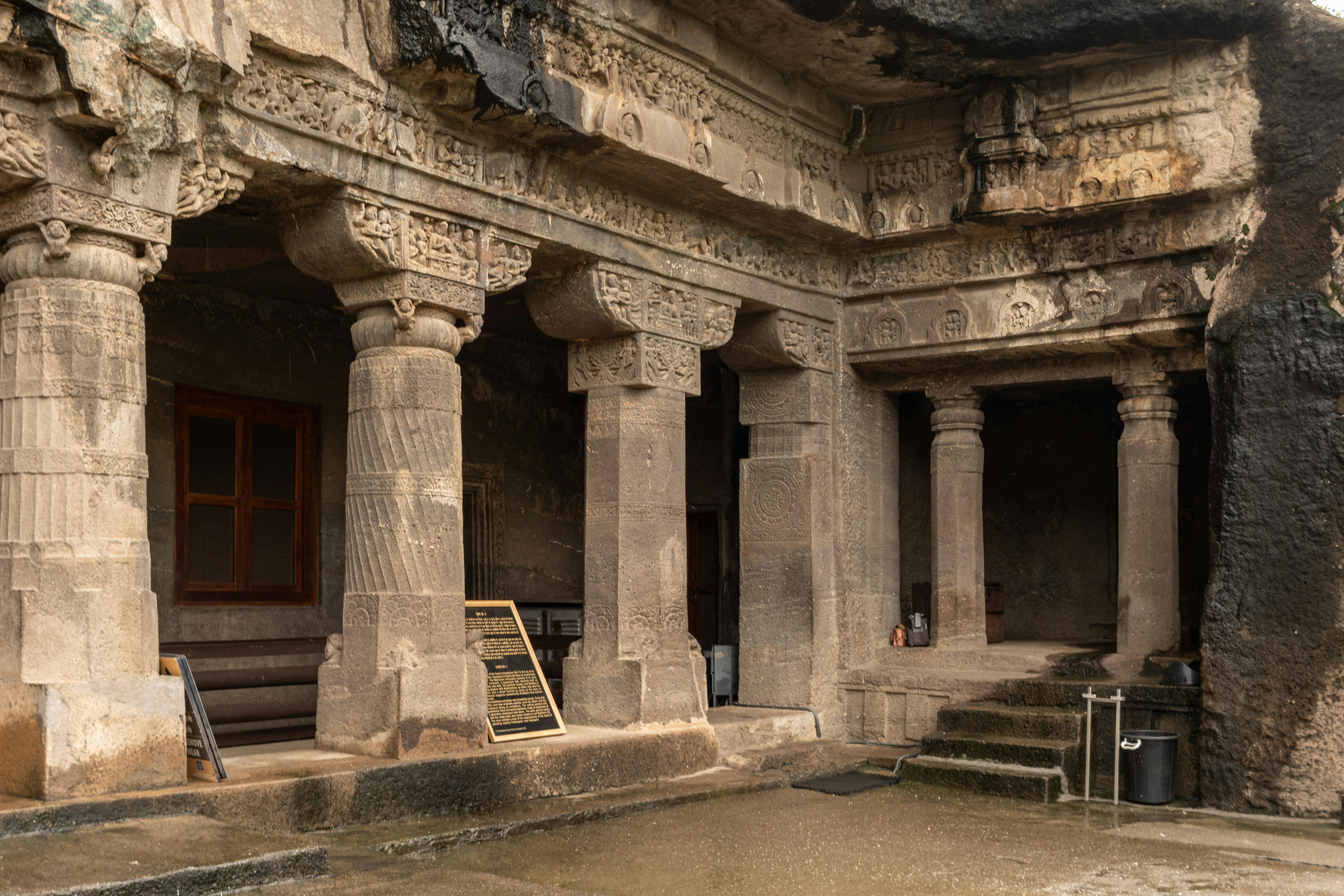The carved stone pillars and ornate rock-cut facade of Cave 1 at the Ajanta Caves in Maharashtra, India