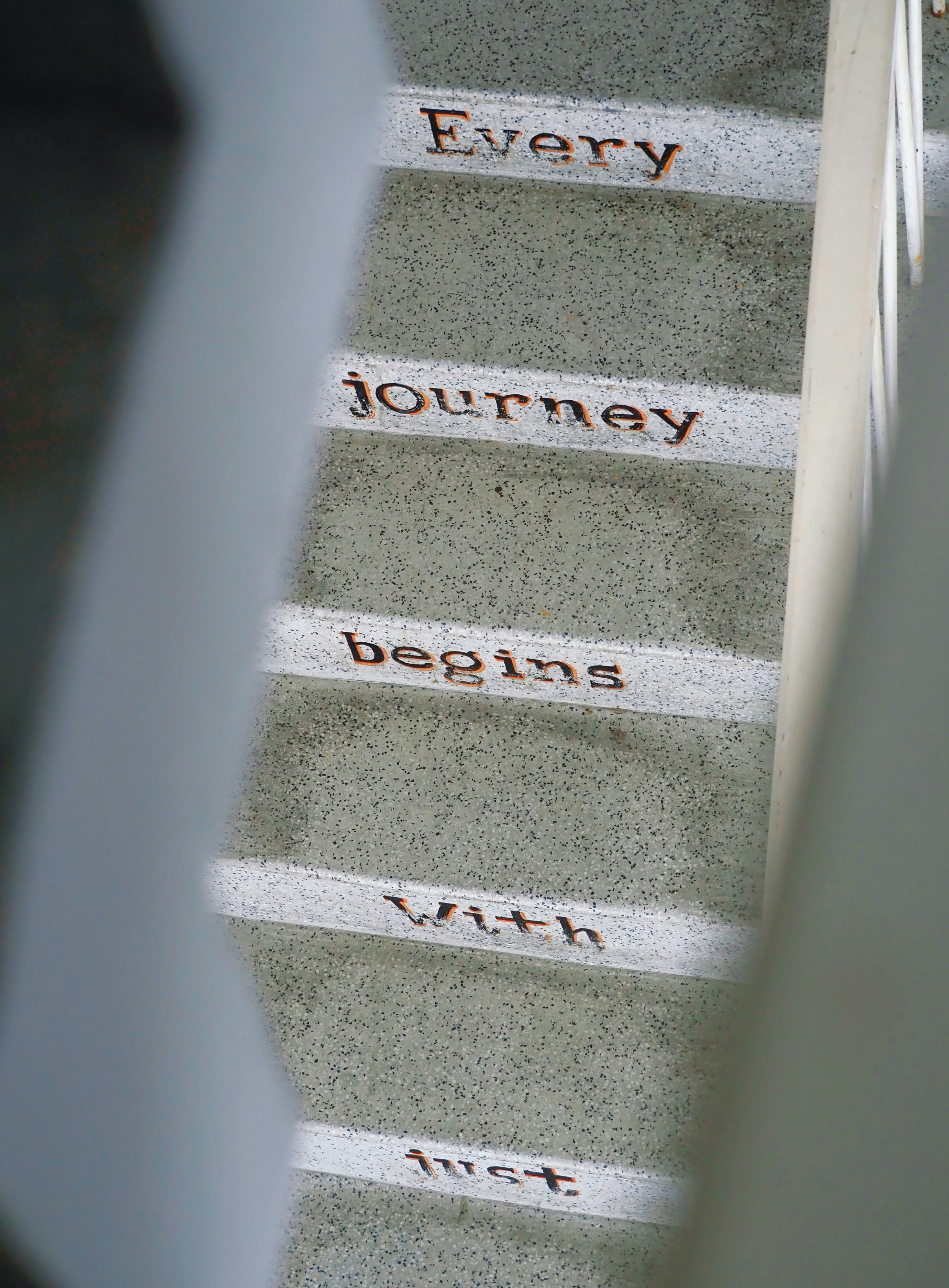 Concrete stairs with the words Every journey begins with just painted on the risers