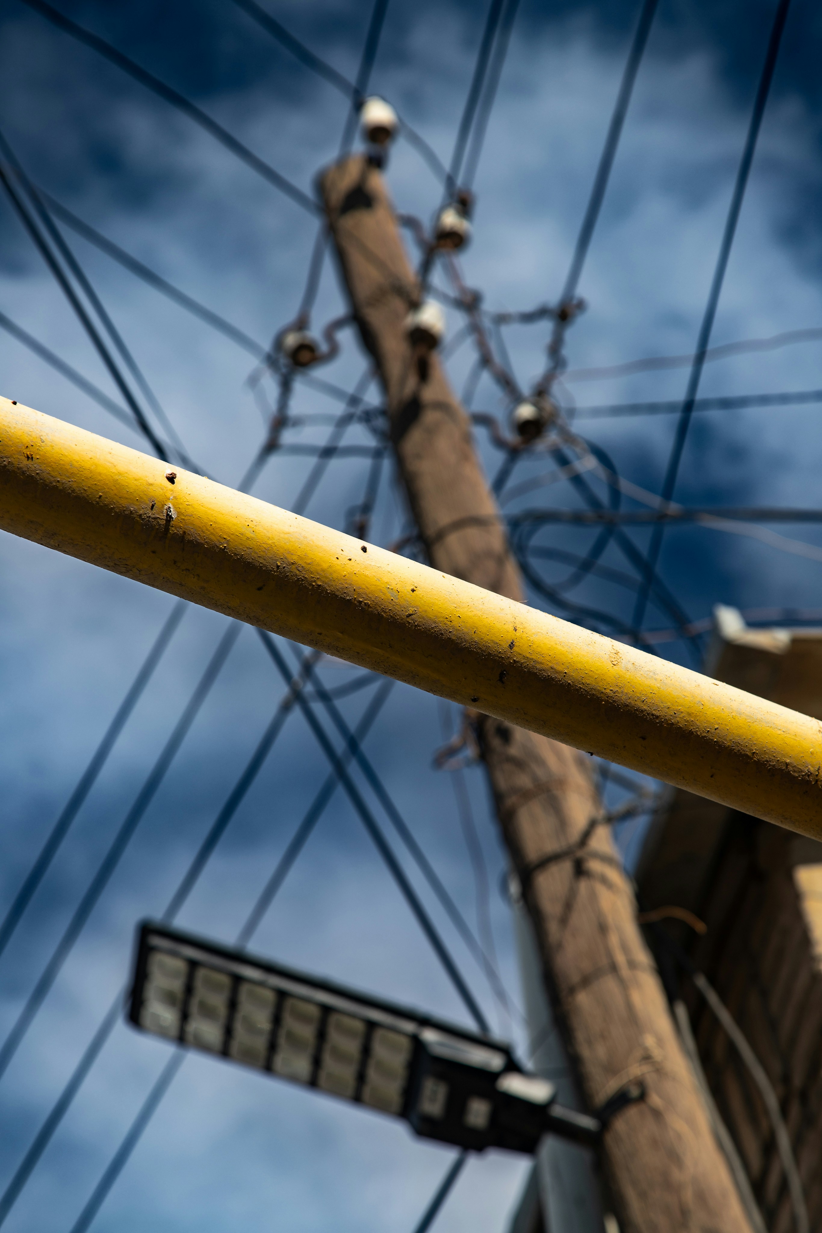 A yellow pipe crossing in front of a wooden utility pole with power lines