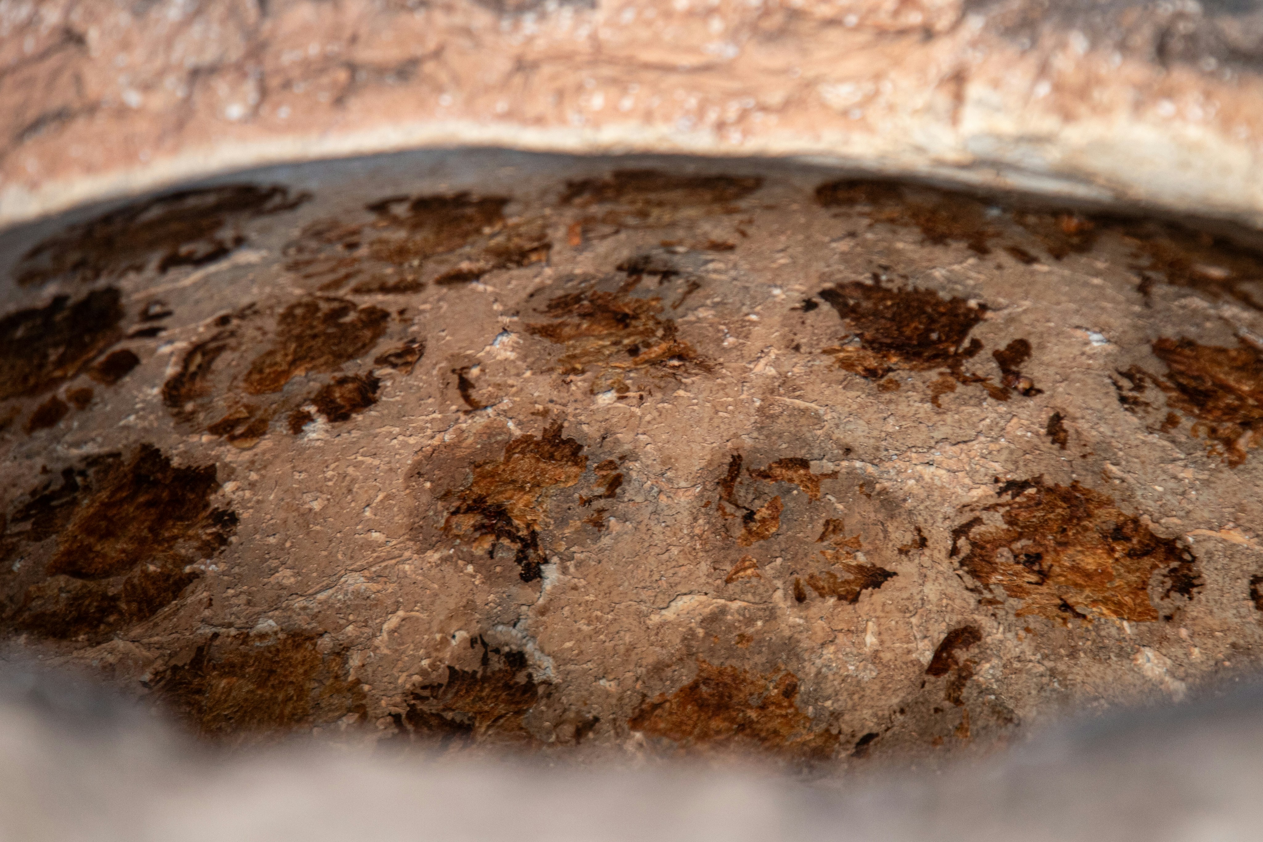 The interior of a clay tandoor oven with dark charred spots on the textured walls