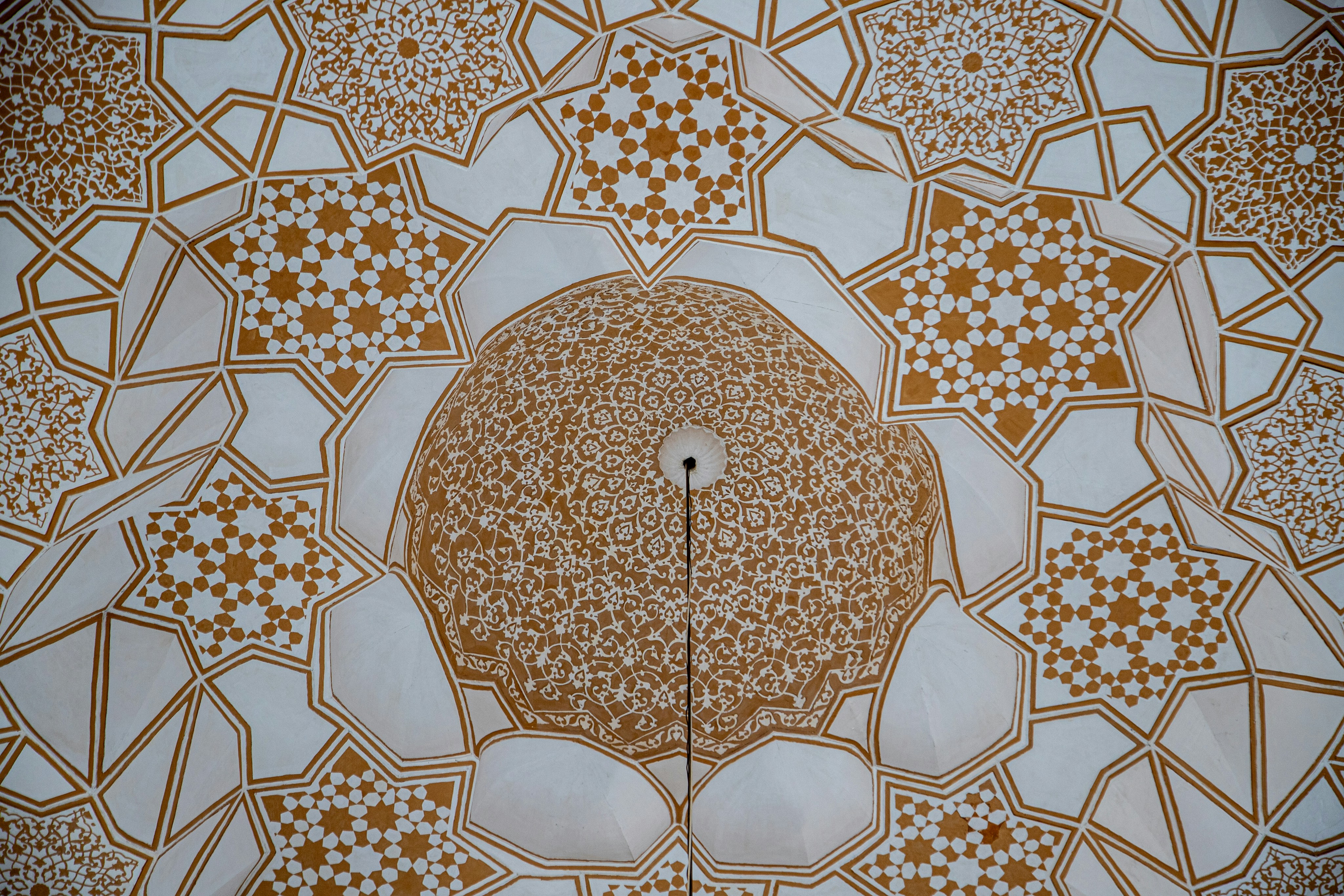 Intricate gold and white geometric patterns on a vaulted ceiling with a central dome