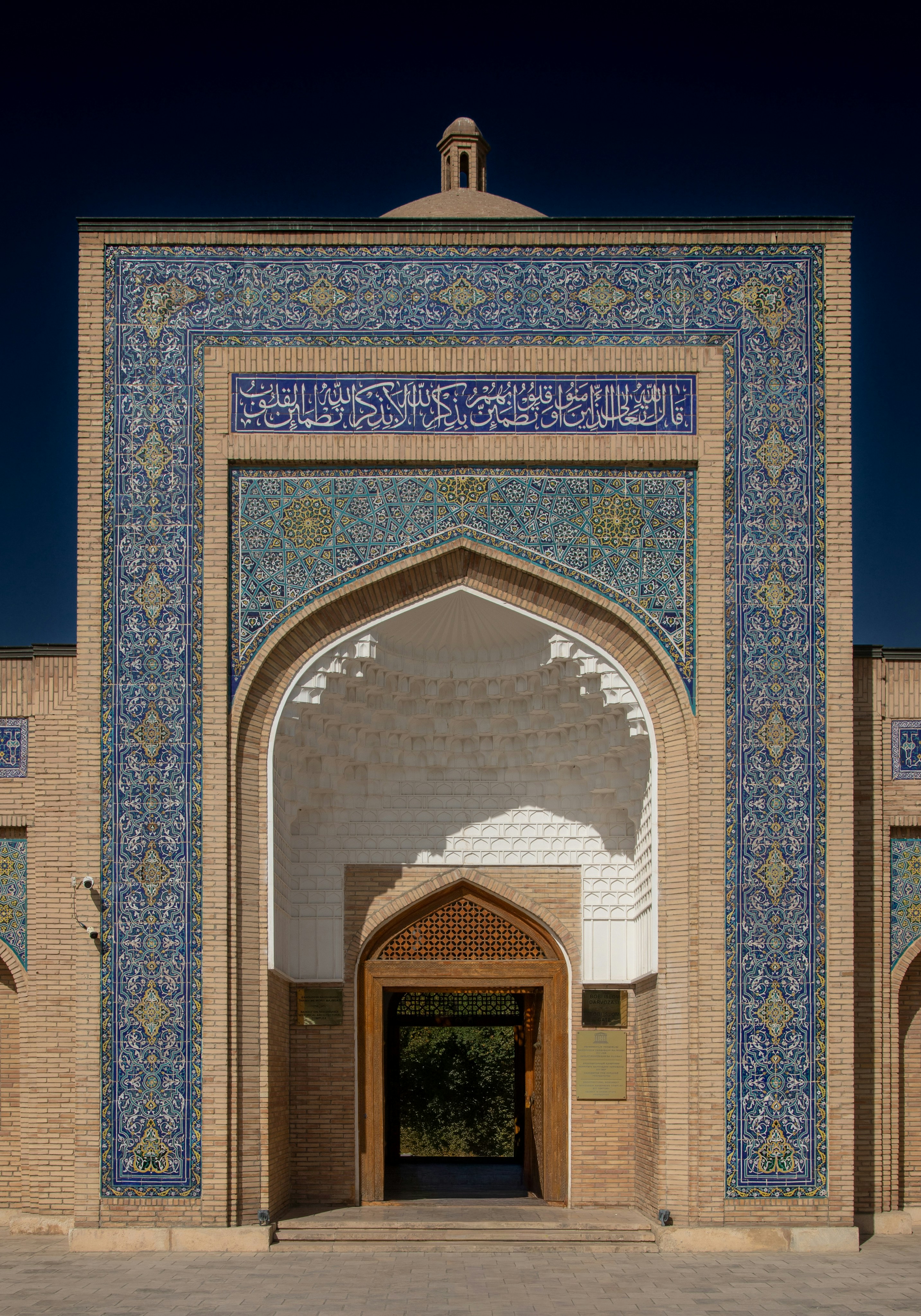The ornate tiled entrance of the Samanid Mausoleum in Bukhara under a clear blue sky