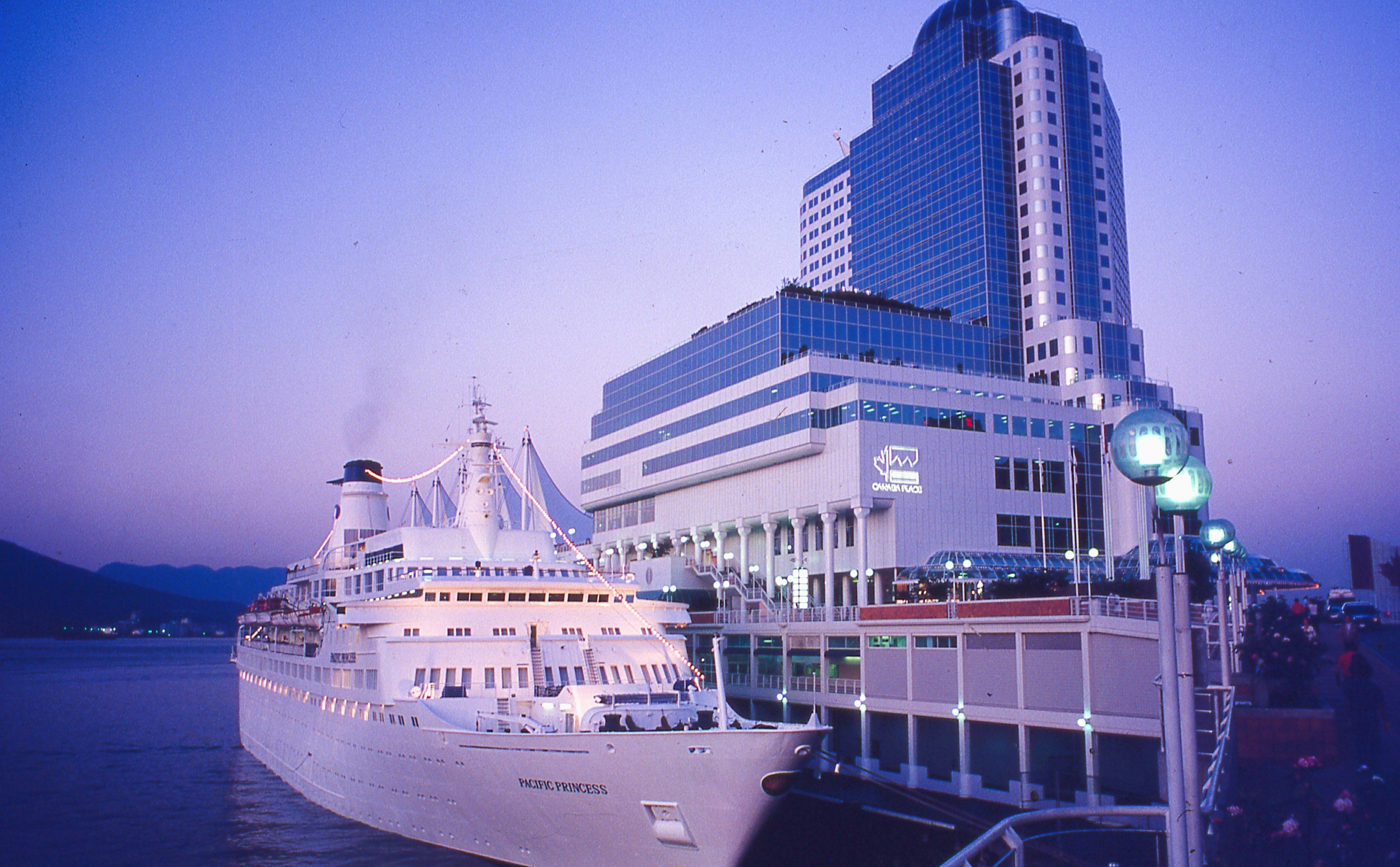 Cruise ship docked alongside the Canada Place terminal pier at dusk.