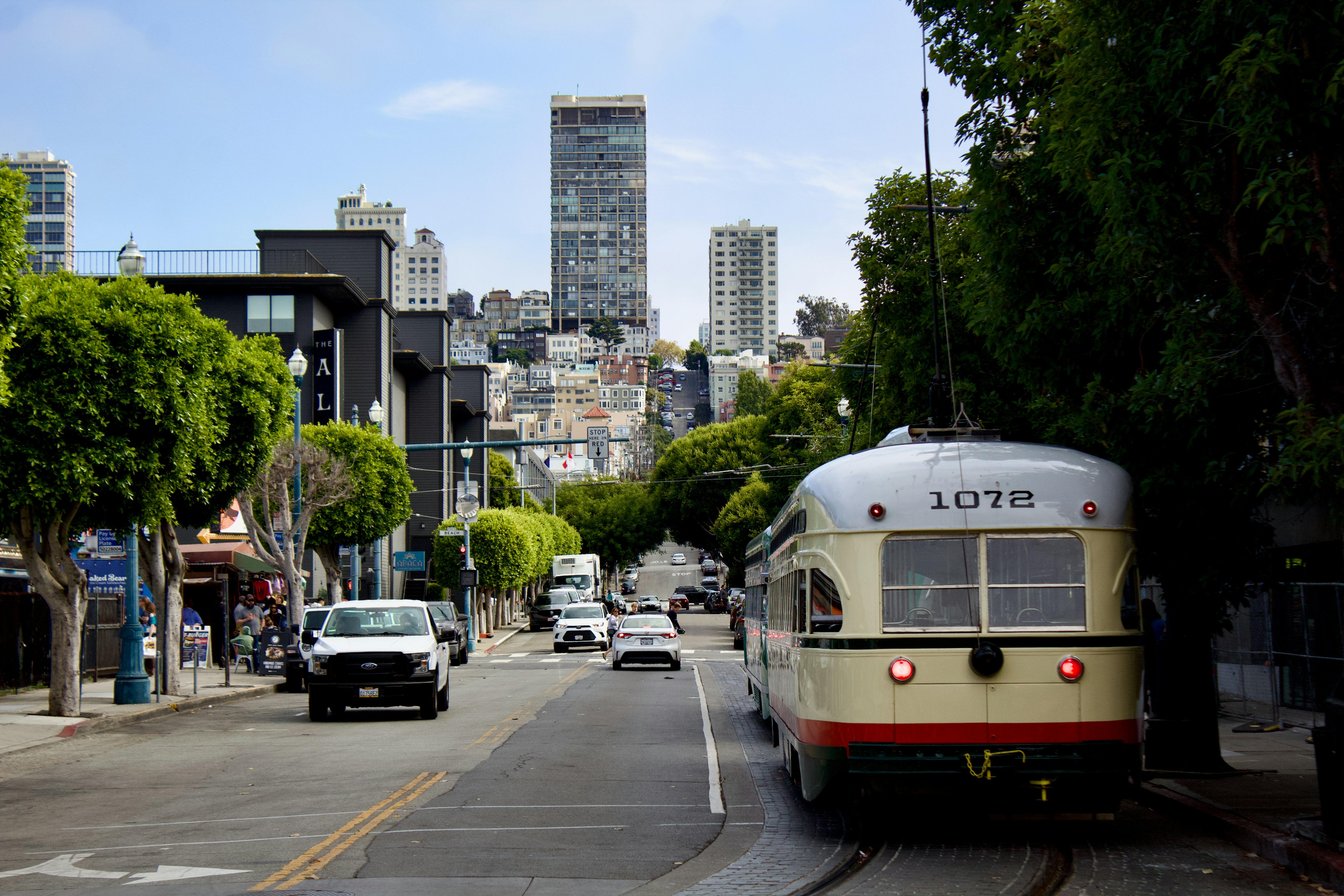 A vintage streetcar traveling down a city street in San Francisco with tall buildings in the background