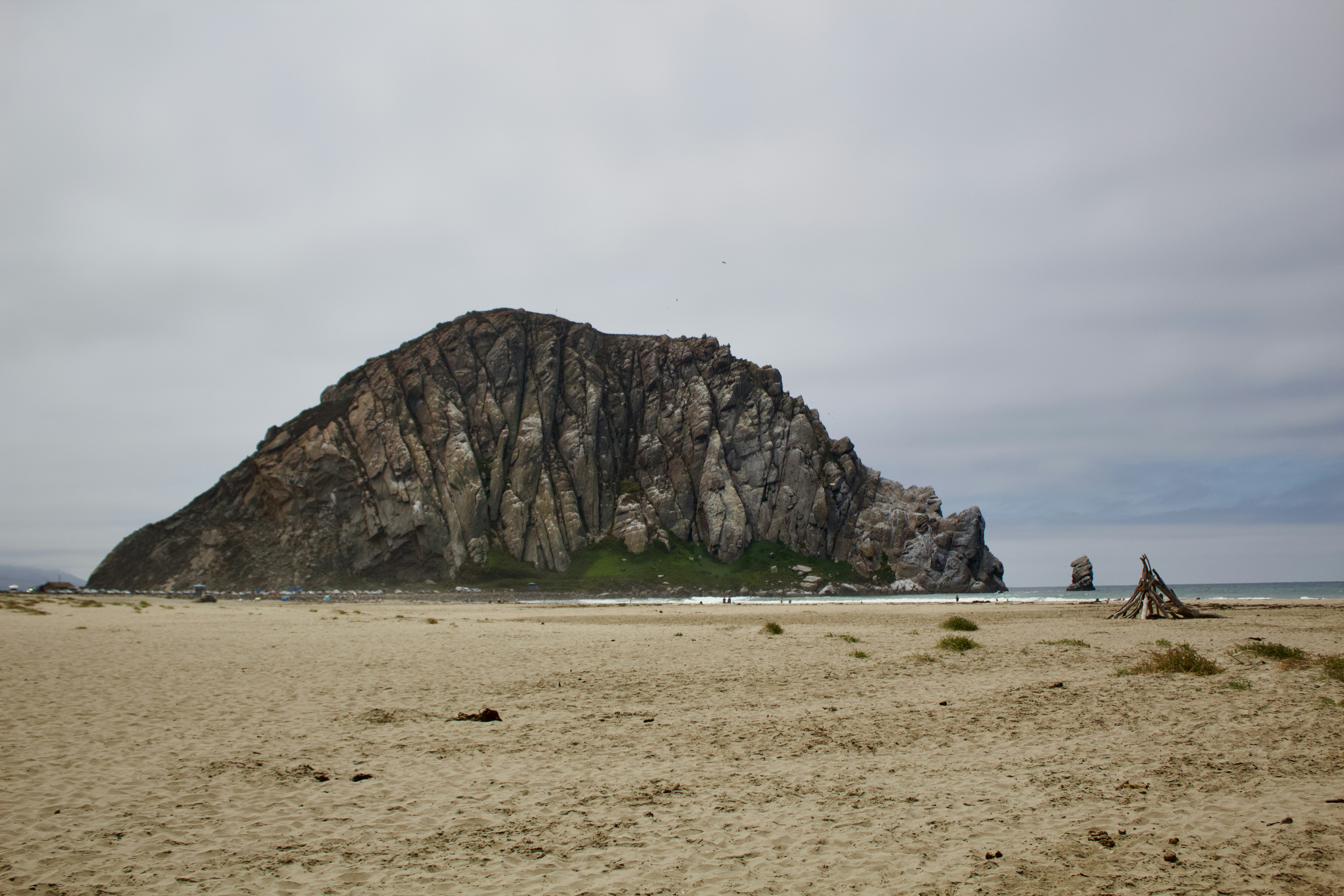 Morro Rock rising above a sandy beach under a cloudy sky in Morro Bay